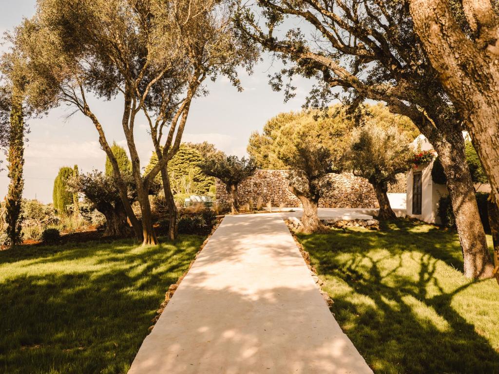 An elegant wedding ceremony setup features a domed gazebo adorned with peach and pink floral arrangements and lush greenery. White chairs line the aisle.