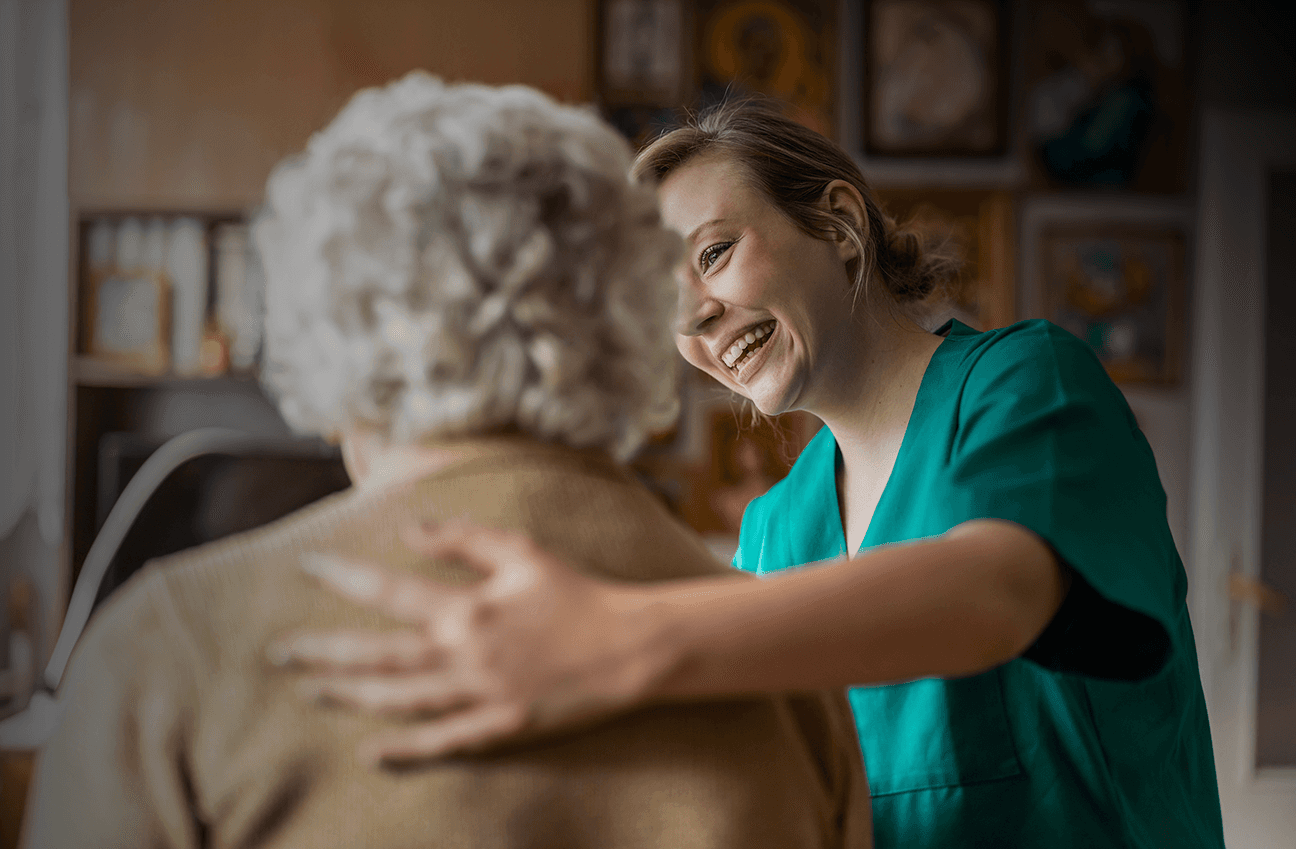 Caregiver placing a hand on an older adult’s shoulder, illustrating how human-centered, data-driven operational improvements can strengthen service delivery across settings such as senior living and healthcare.