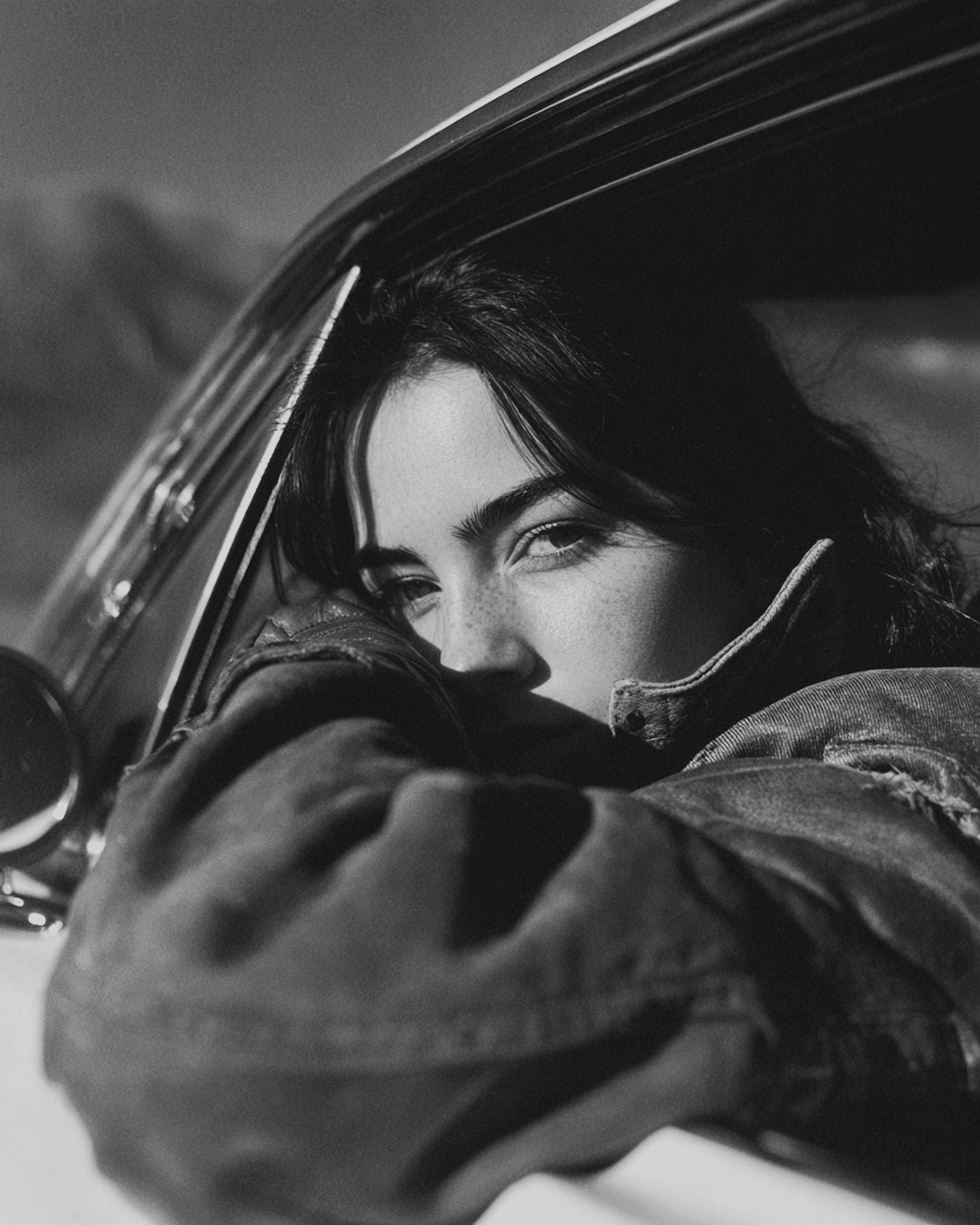 A woman is sticking her head out, looking from a car window.