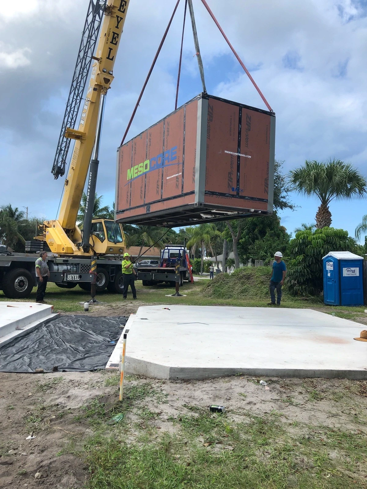 Crane delivering a modular ADU unit onto a prepared foundation at a residential property.