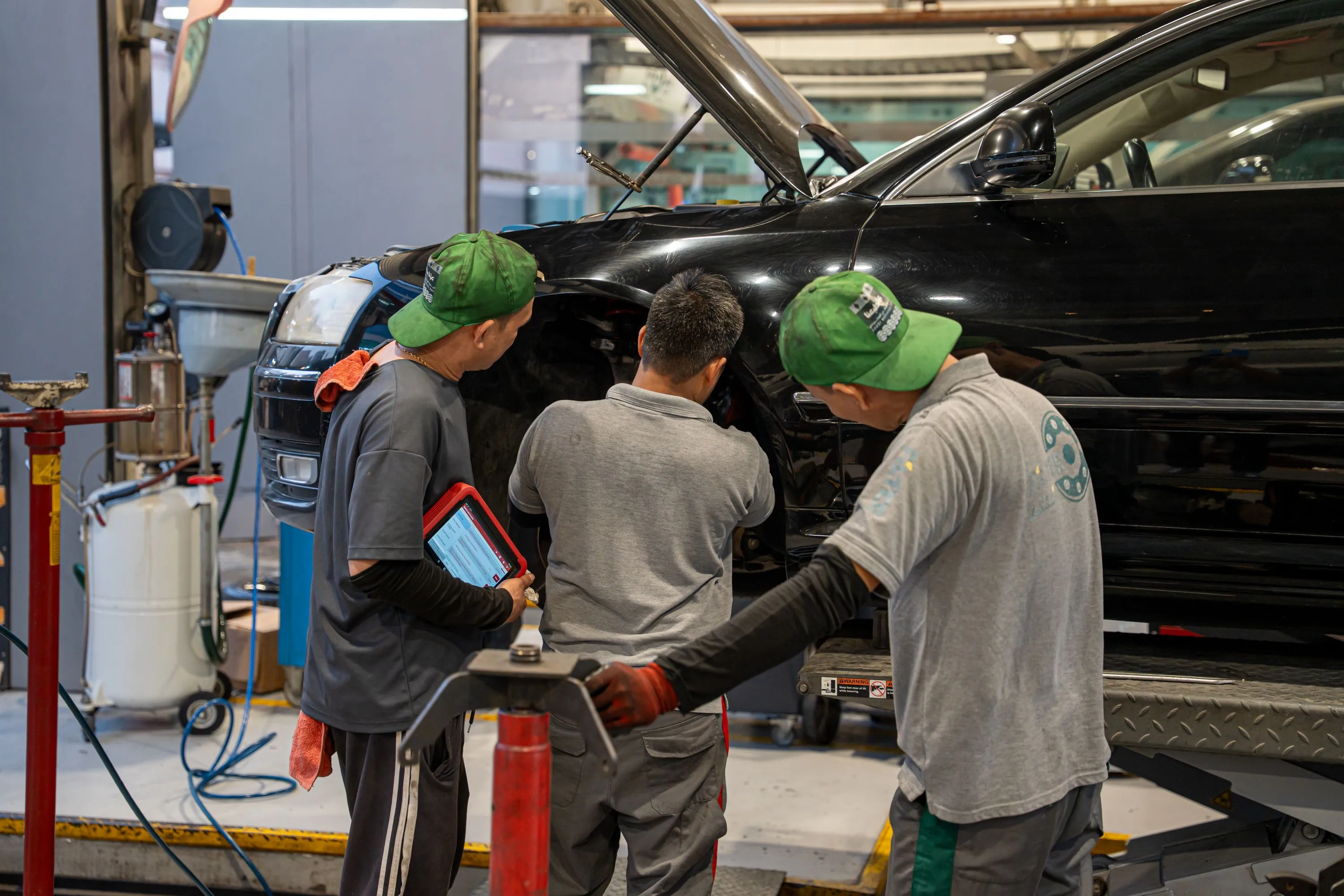 رجل يعمل على محرك سيارة مع أدوات في مرآب يحتوي على معدات وإمدادات متنوعة.