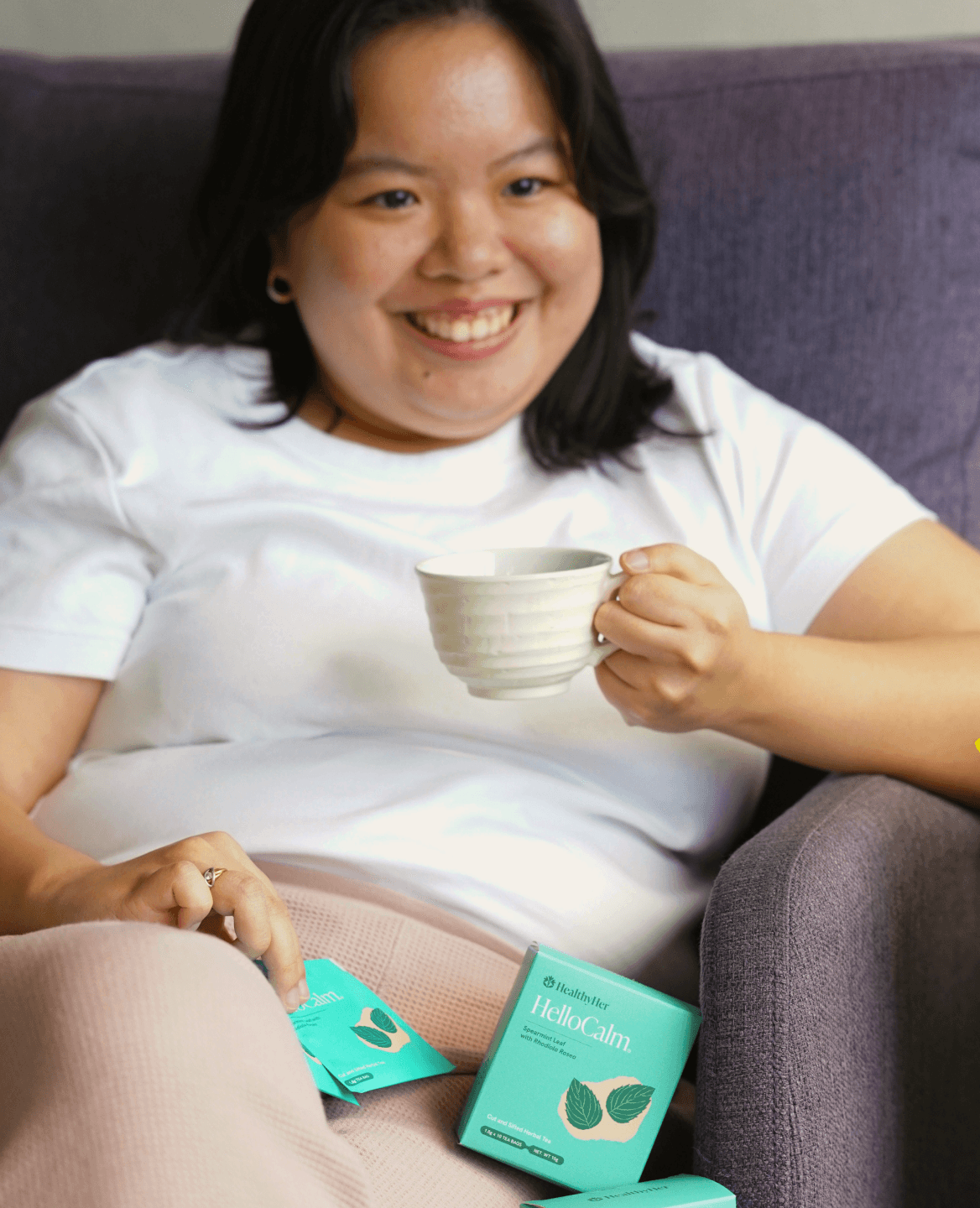 Filipina woman smiling holding a cup of HelloCalm herbal tea for PCOS