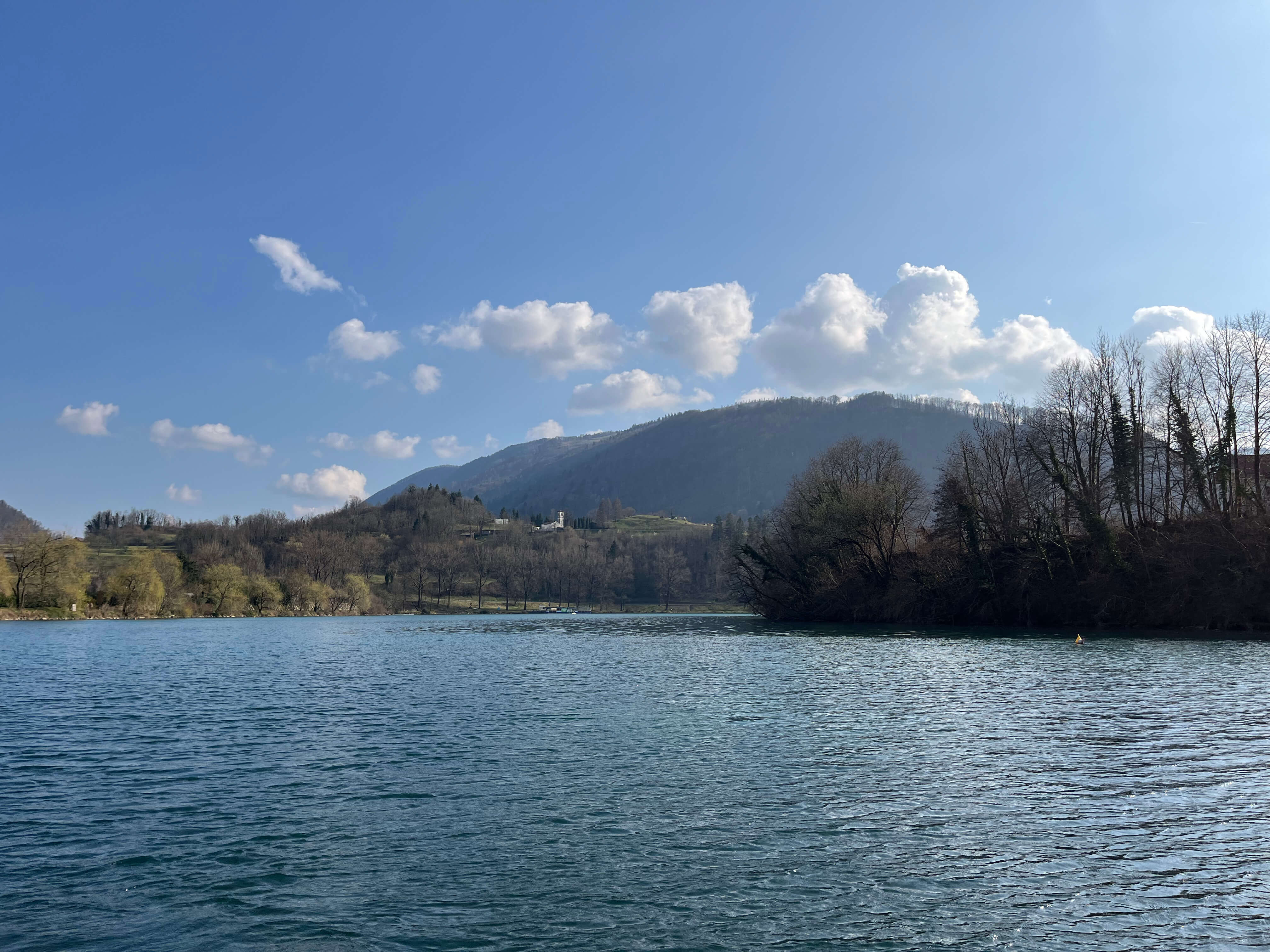 Boat-based marble trout fishing in Slovenia with angler casting streamer along rocky shoreline