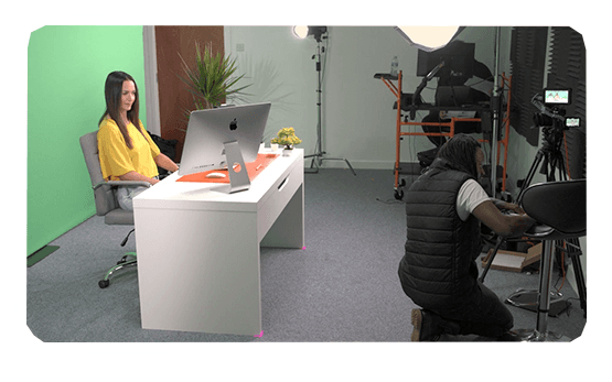 Photograph of a small video studio production with  an office scenario, an actress and a videographer