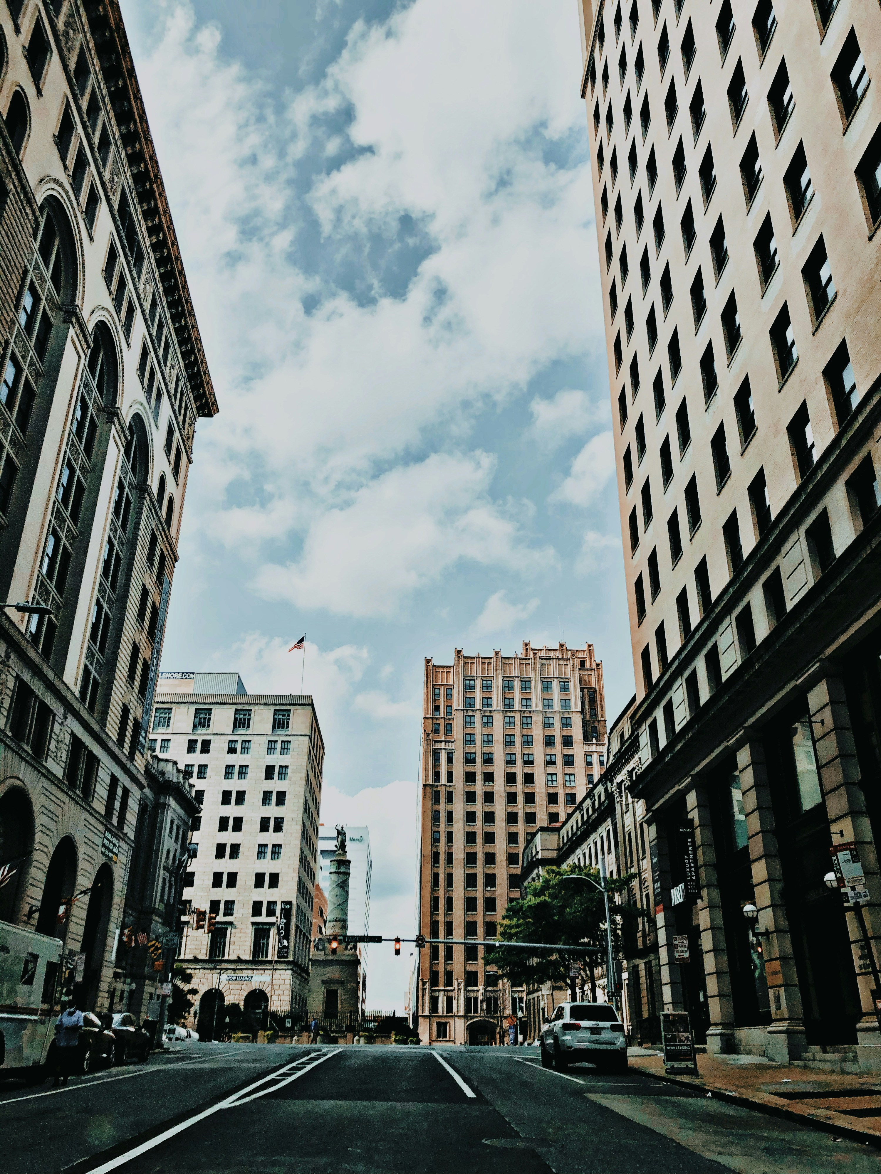 An empty street in Baltimore with tall building stretching up to blue skies.