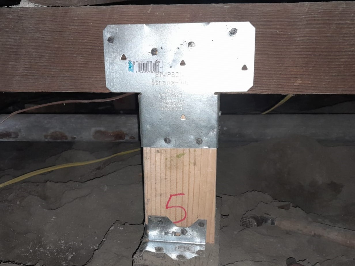 A modern house with large windows and a flat roof, surrounded by greenery against a clear blue sky.