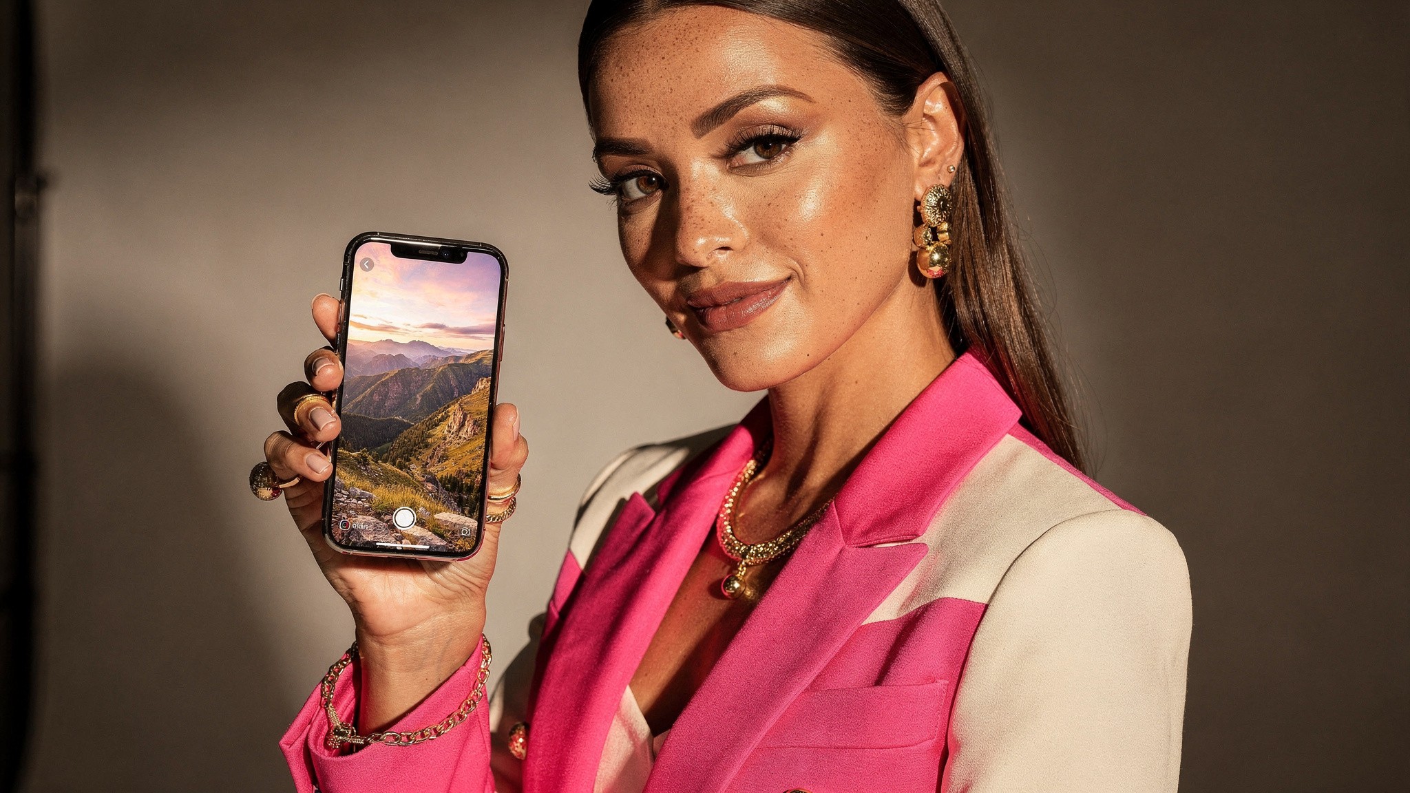 Travel creator holding a phone showing a wide landscape Instagram photo