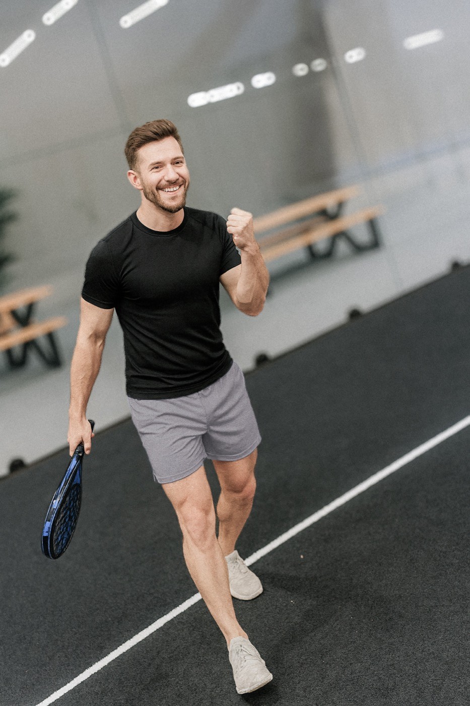 Lächelnder Padelspieler jubelt nach einem Punktgewinn – Energie, Freude und Dynamik auf dem schwarzen Padelnero Court.
