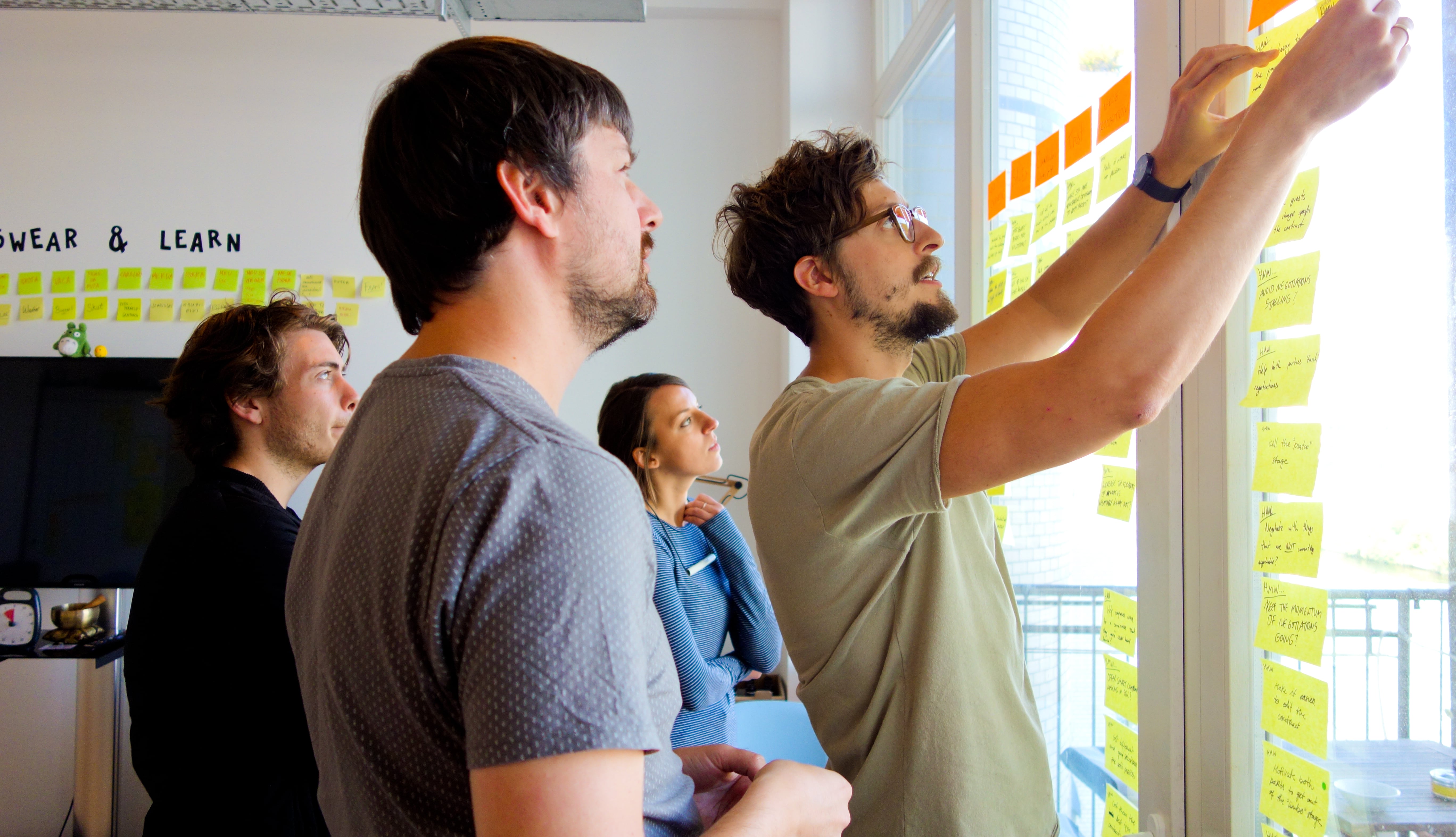 Team members placing sticky notes on a glass wall during a facilitated workshop session