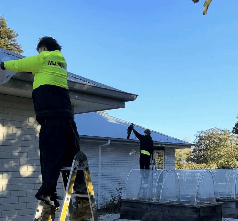Max clearing debris from gutters on a Hamilton home during a professional gutter clean
