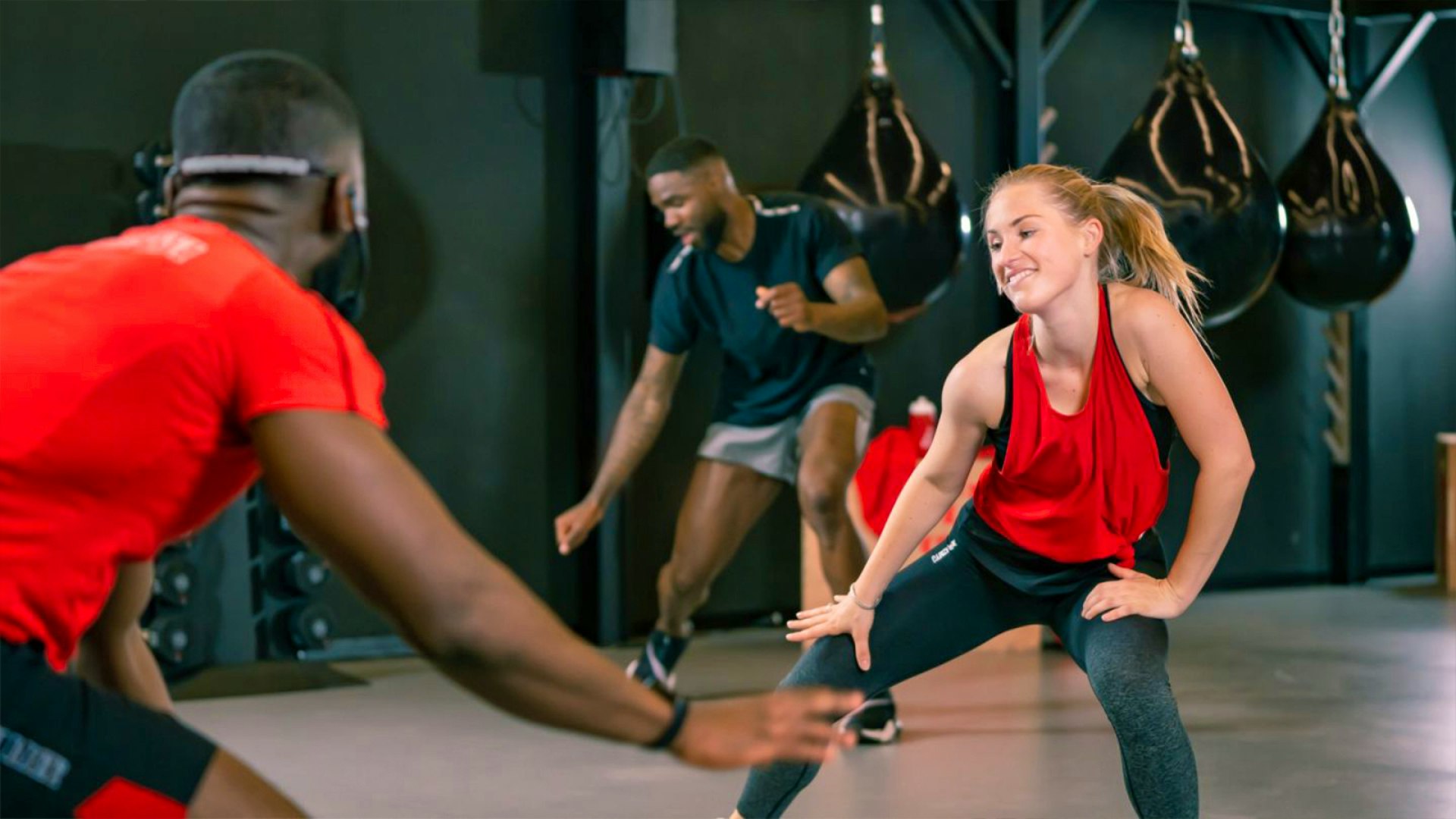 Sportcity — group fitness class in a dark training studio with boxing bags and red and black sportswear — Soda Studio case study