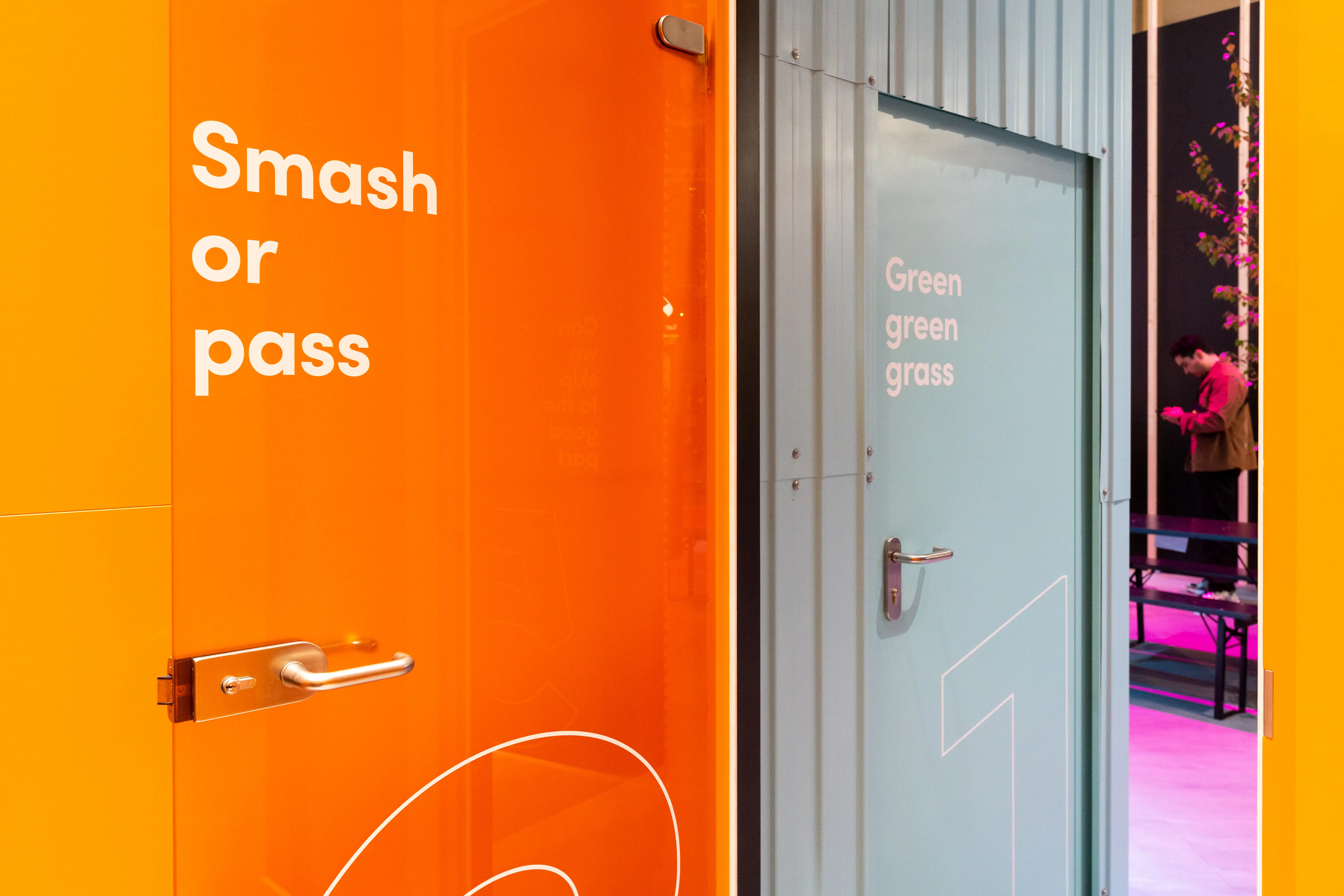 Detail of the orange Smash or Pass glass door and grey Green green grass door at the TikTok booth at OMR.