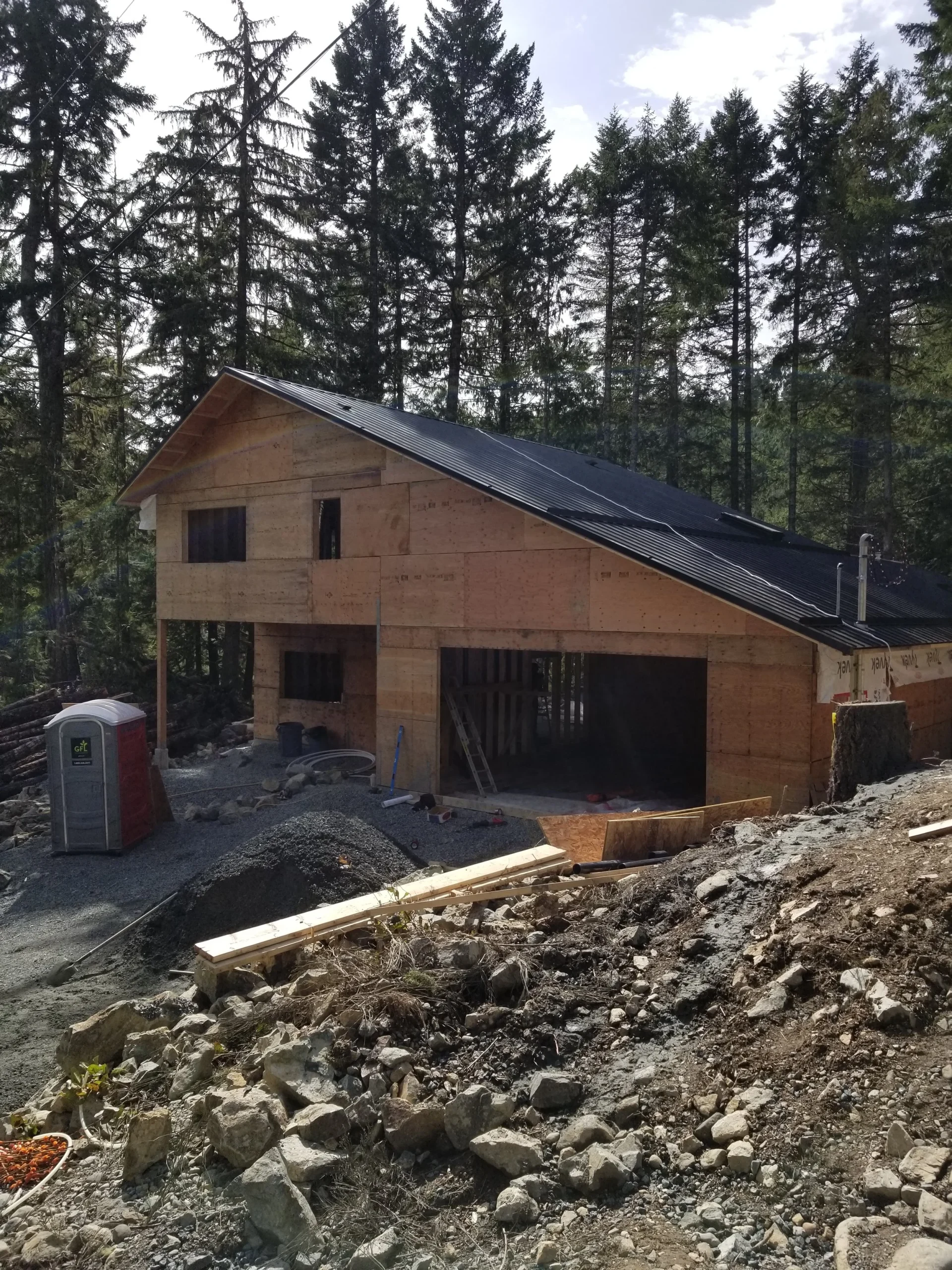 Modern two-story home with large glass windows, warmly lit interiors, and a balcony. Surrounded by trees and a manicured lawn at dusk. Cozy ambiance.