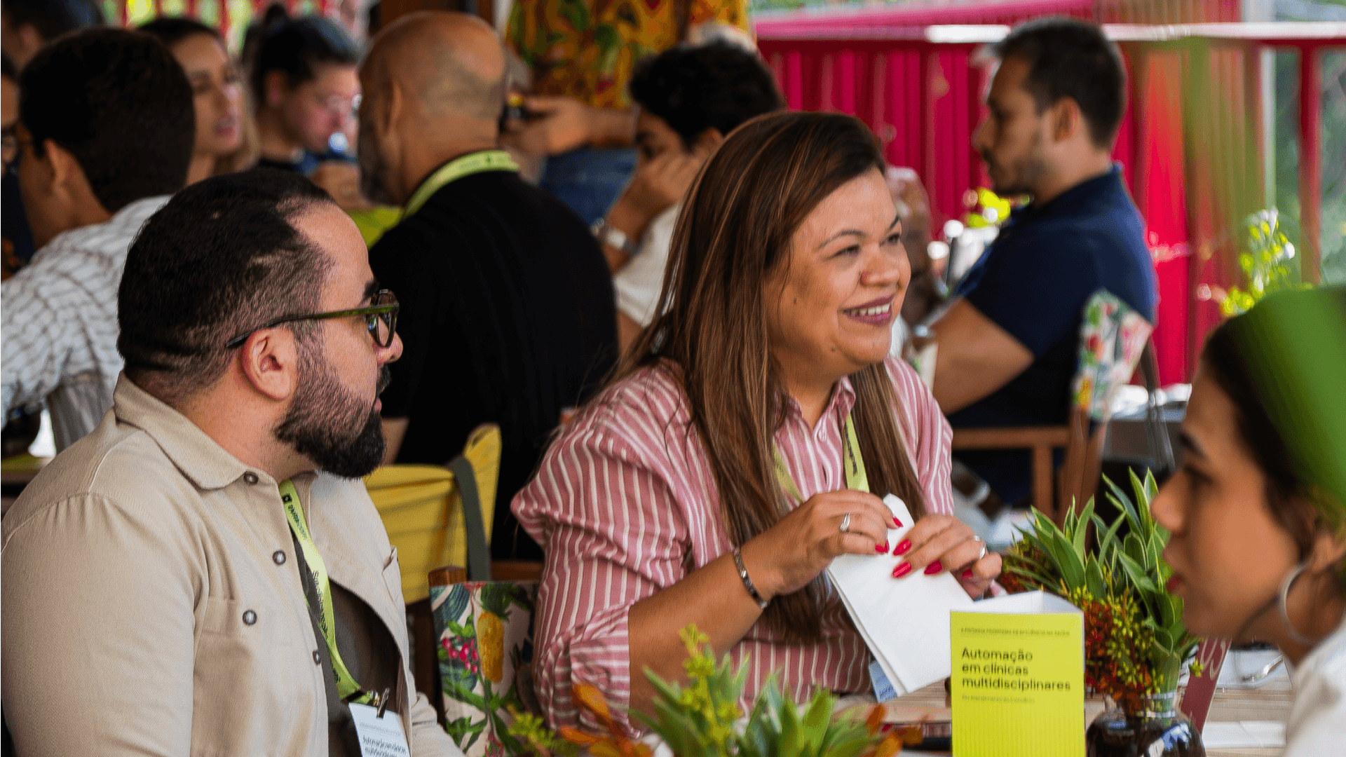 Participantes em evento da Tivita voltado para novas possibilidades em clínicas. A imagem mostra profissionais em uma mesa com materiais sobre automação em clínicas multidisciplinares, destacando a iniciativa da Tivita em promover inovação e conexão no setor de saúde.