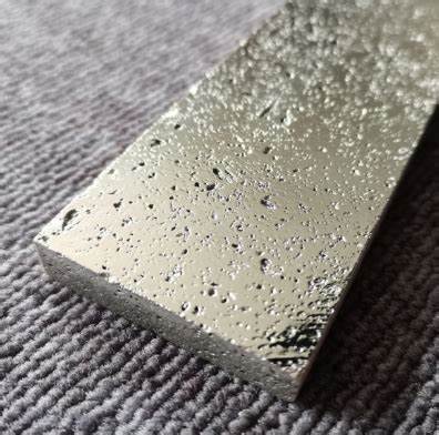 Close-up of an electroplated stone tile with a textured, metallic surface, reflecting light.