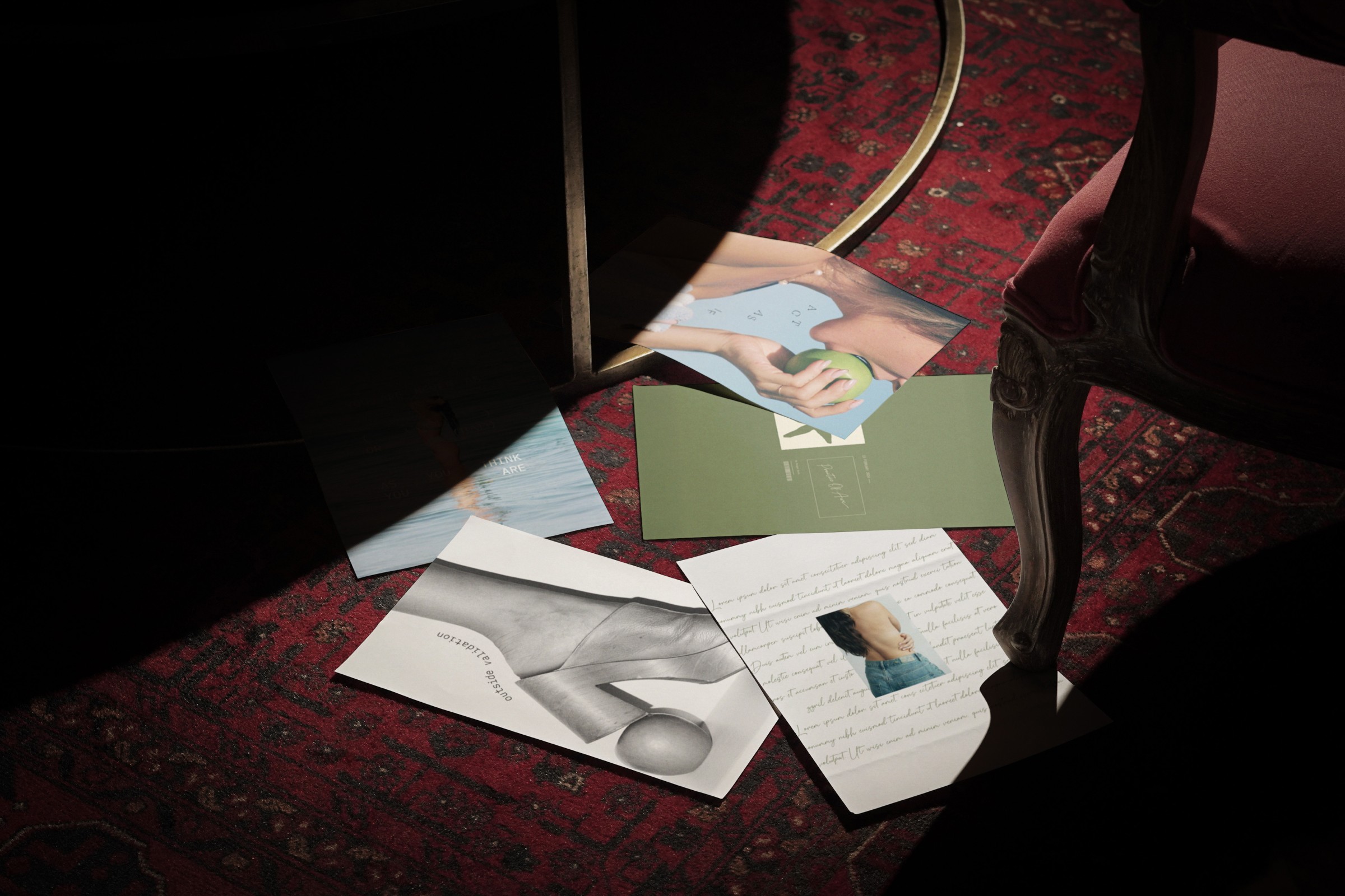 Scattered creative marketing materials on a deep red vintage rug, representing Dazey Bottega’s modern and artistic brand identity.