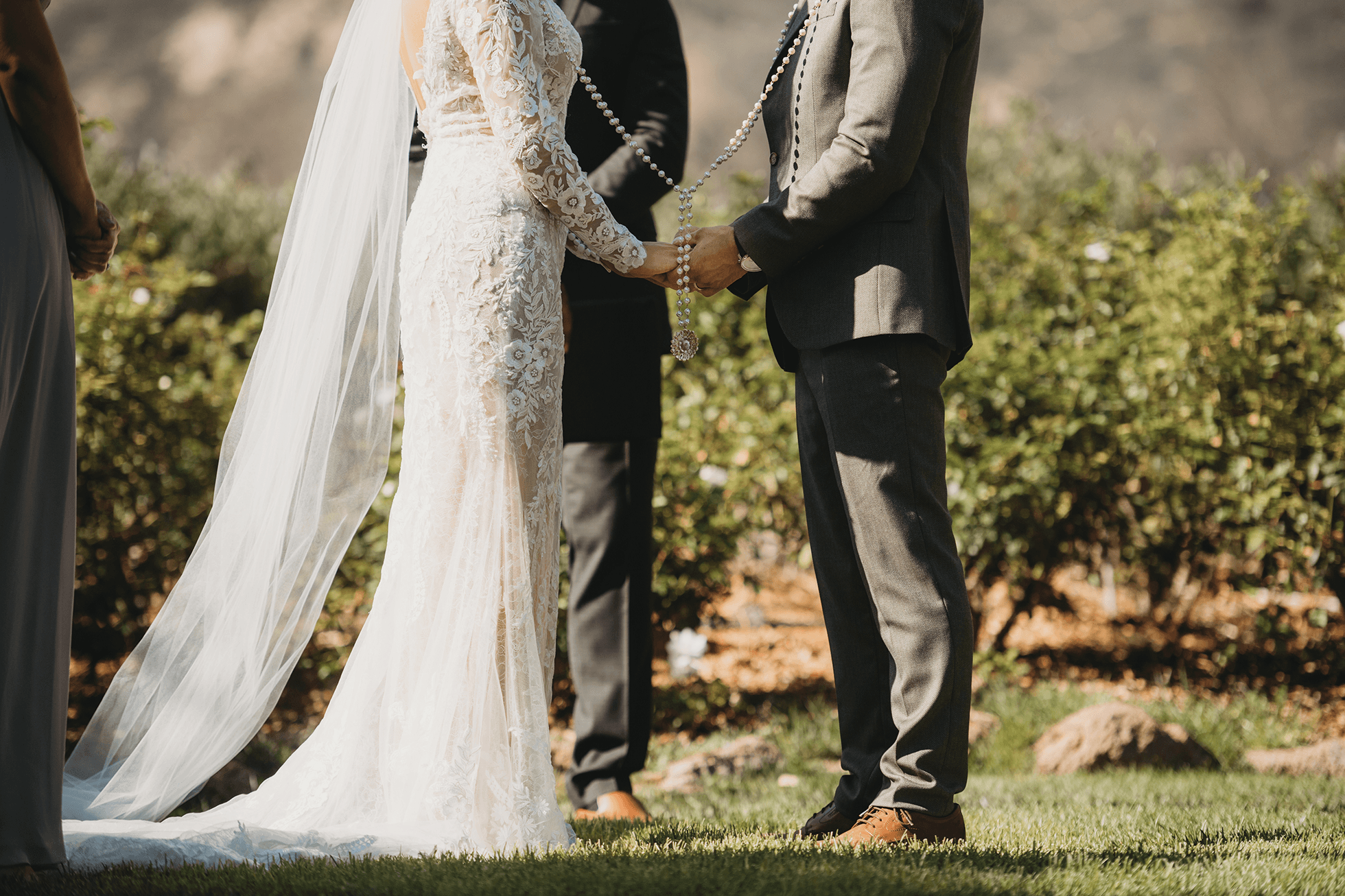 Rosary draped over bride and groom hands during ceremony