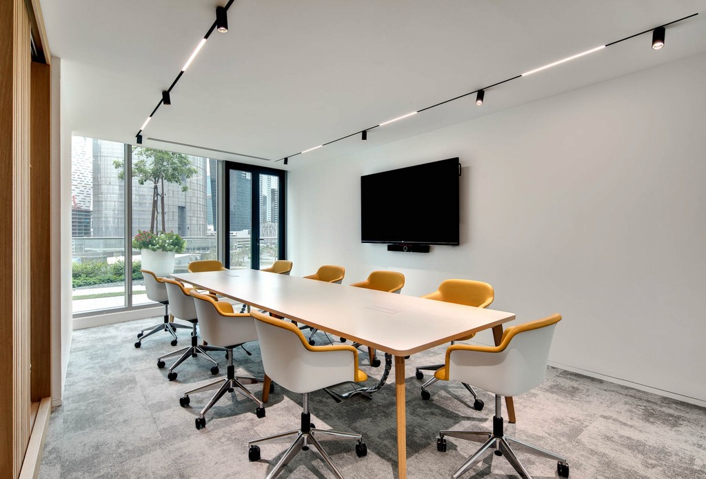 Interior of a conference room with blue chairs and a circular light fixture, part of The Binary by OMNIYAT.