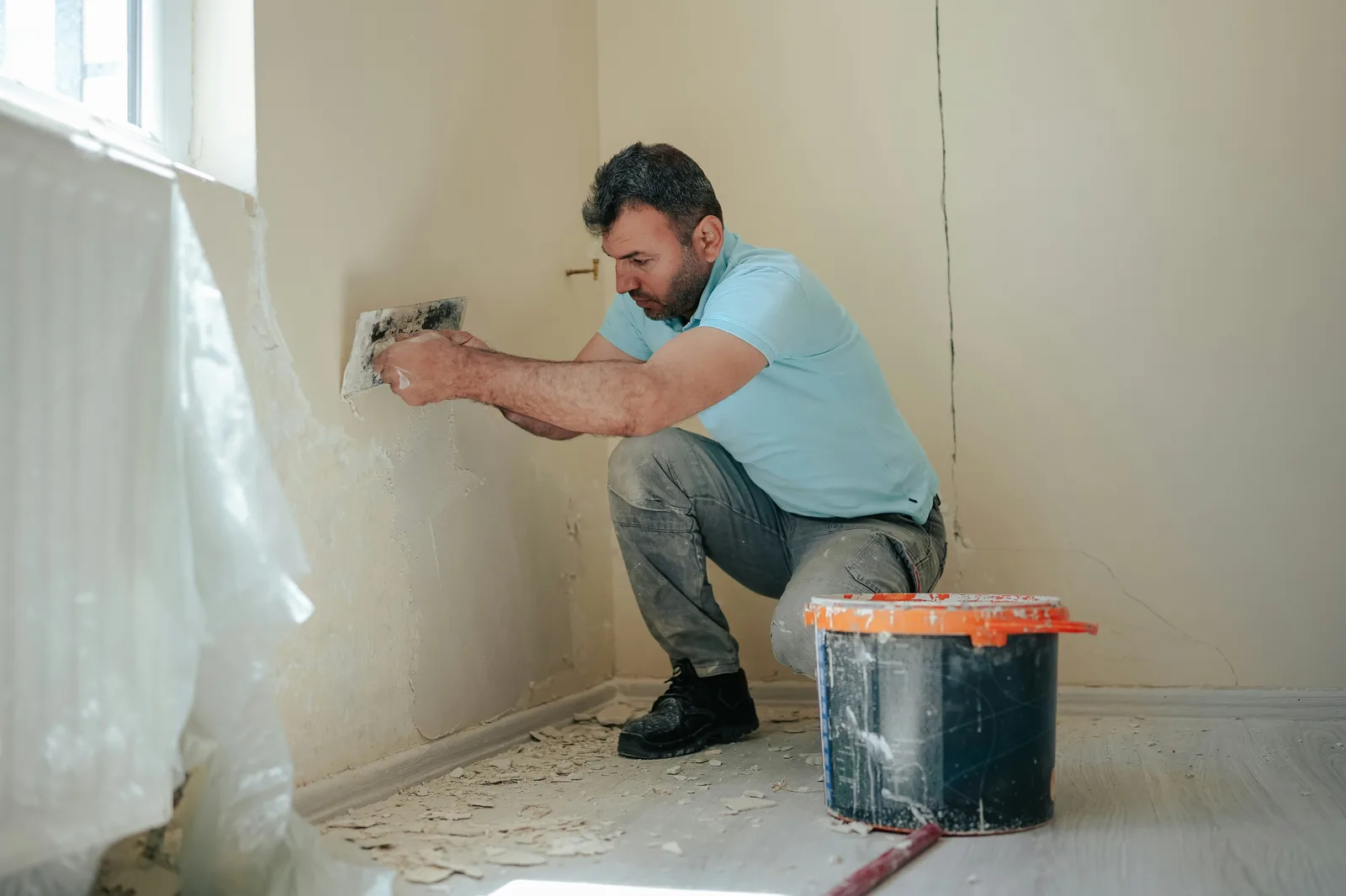 Работник клекнал мажe стена с мистрия до кофа и прозорец