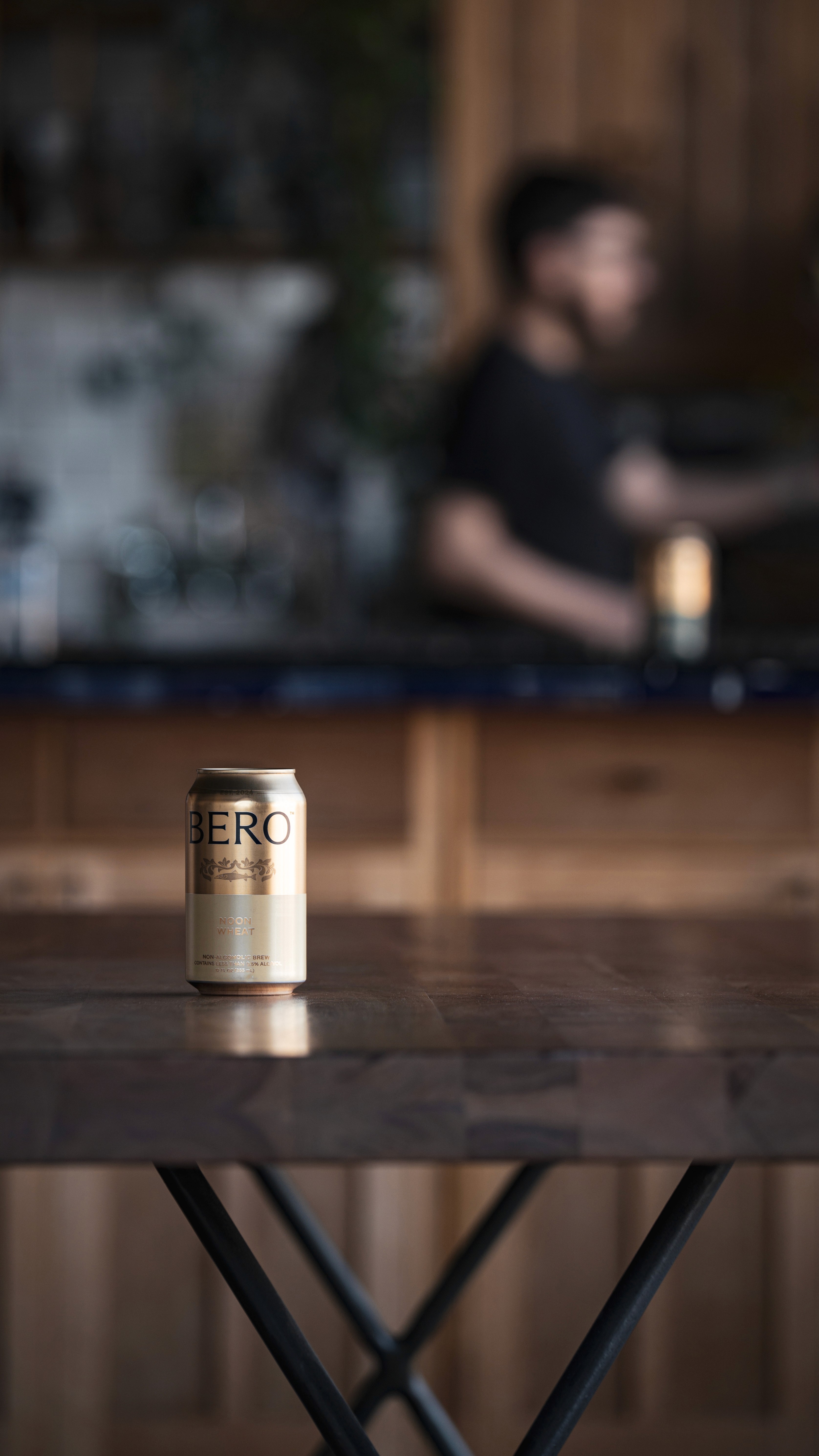 Single BERO can centered on a wooden bar with a softly blurred room in the background.