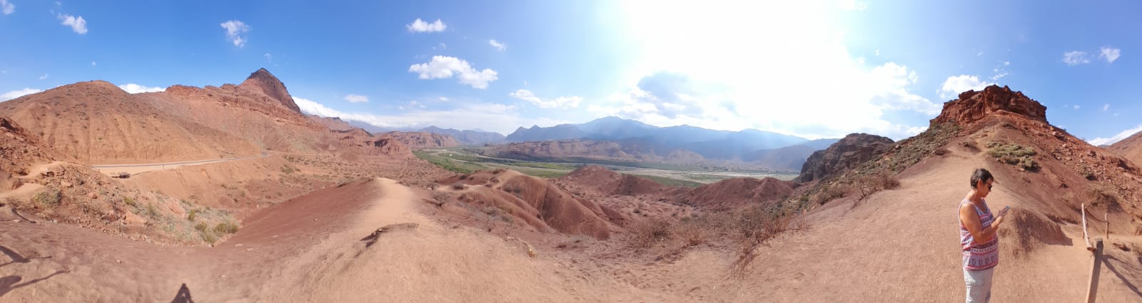 Mujer sentada sobre un tronco frente a una cascada doble en un bosque frondoso de Argentina.