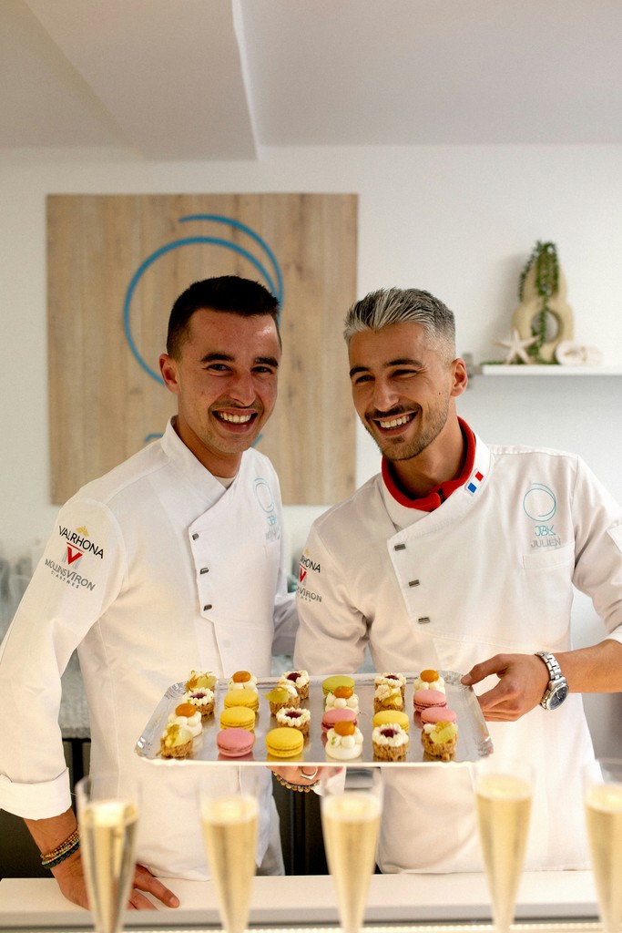 A couple of men standing next to each other in a kitchen