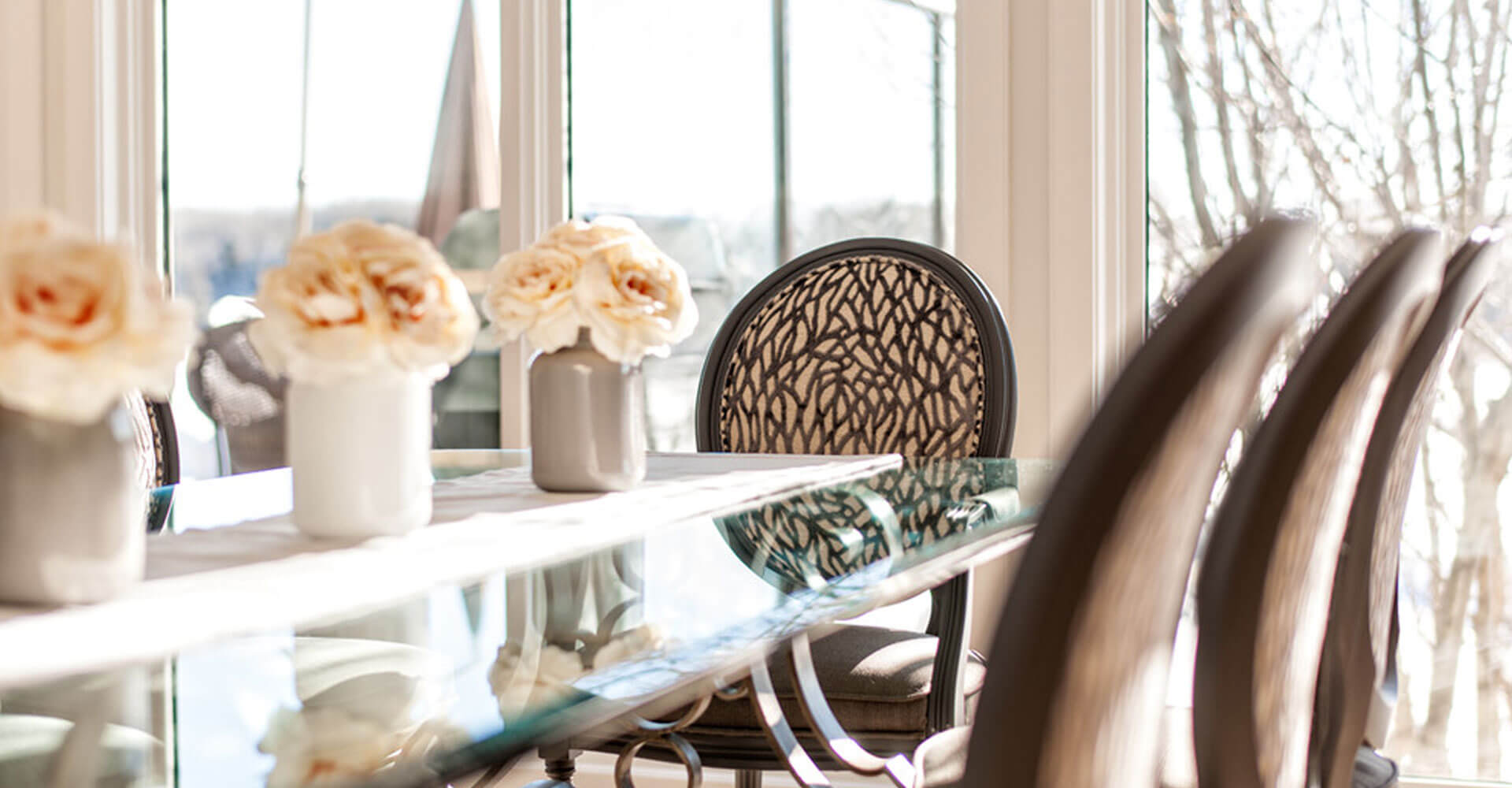 Image of Luxury dining area with glass table, elegant chairs, and vases with roses, KHD Homes interior design.