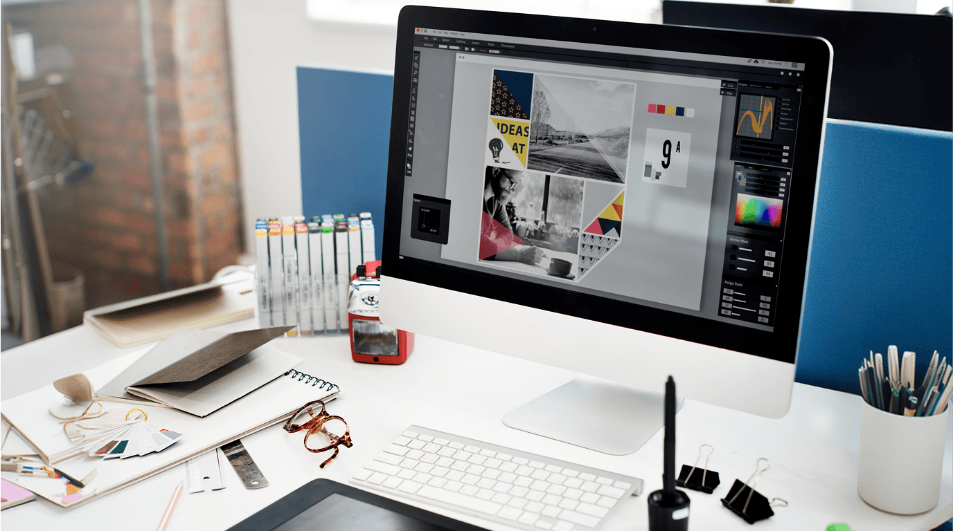 A branding agency designer's desk with a computer screen showing a mood board layout, colour swatches, markers, and design tools — Penguincil Design