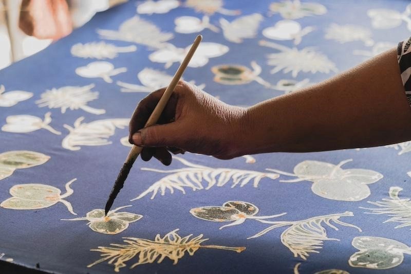 Traditional batik wax-resist technique demonstration — canting tool detail.
