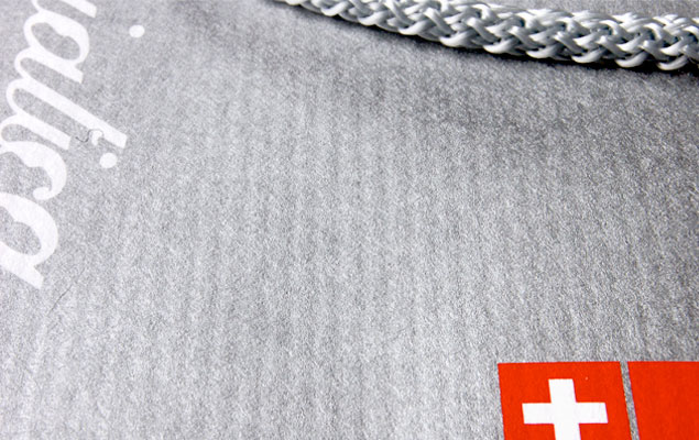 Macro detail of Italian ribbed paper stock – Pantone Silver print with Swiss cross stripe. Adriatica branded paper bag, produced in Kraków.