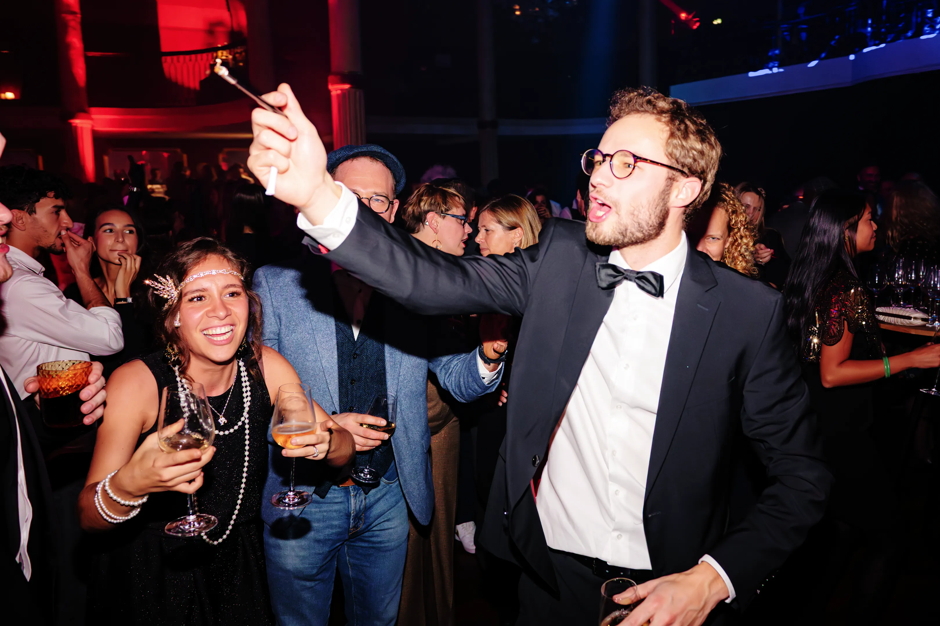 Groupe de participants en tenue années 30 levant leurs verres lors d’une soirée de gala animée