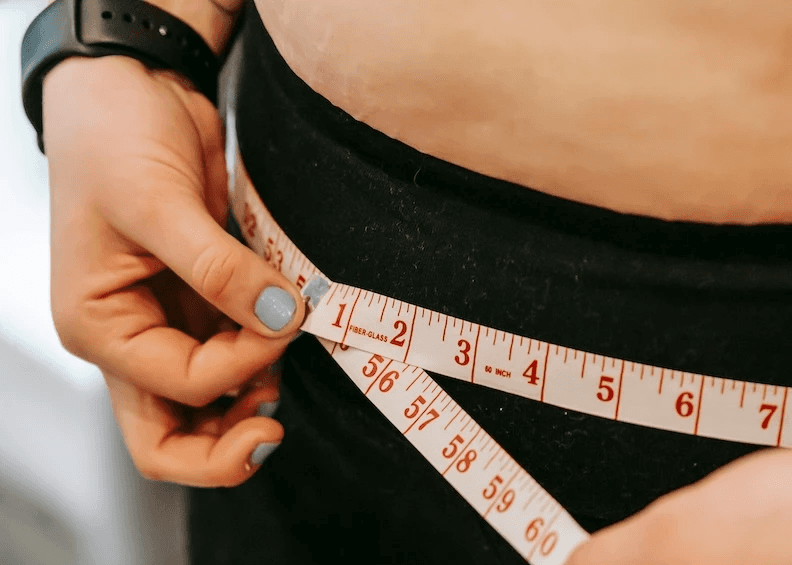 Person using measuring tape to measure waist