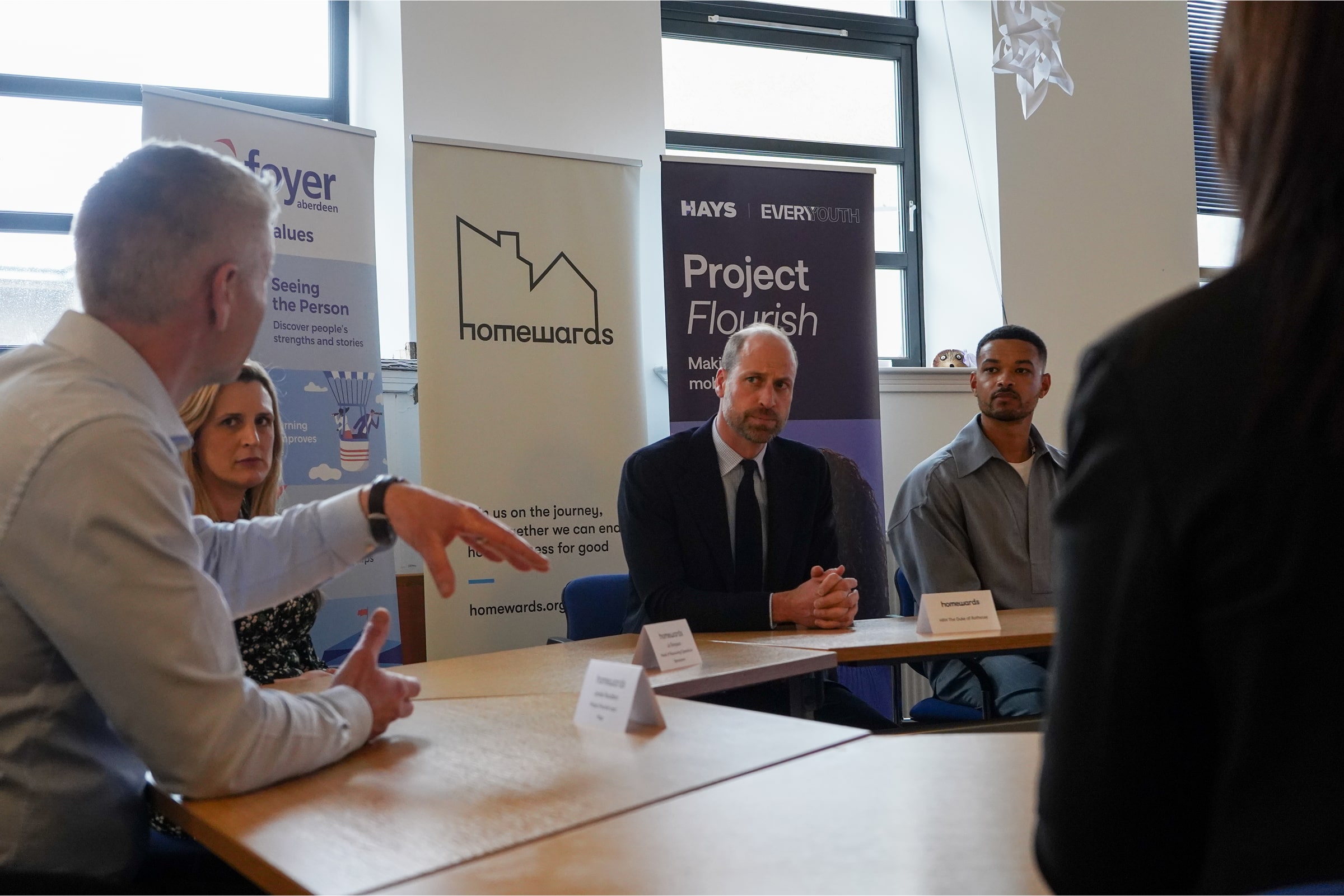 Prince William and Steven Bartlett listen to a roundtable attendee talk as part of an employment event