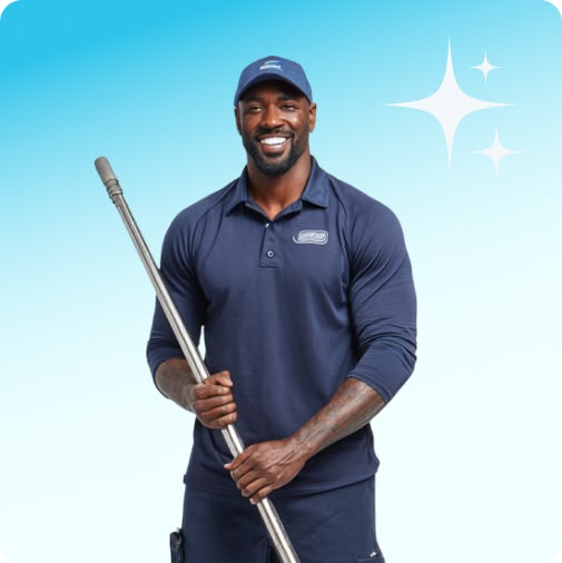 A smiling man holds a basket of cleaning supplies against a light green background.