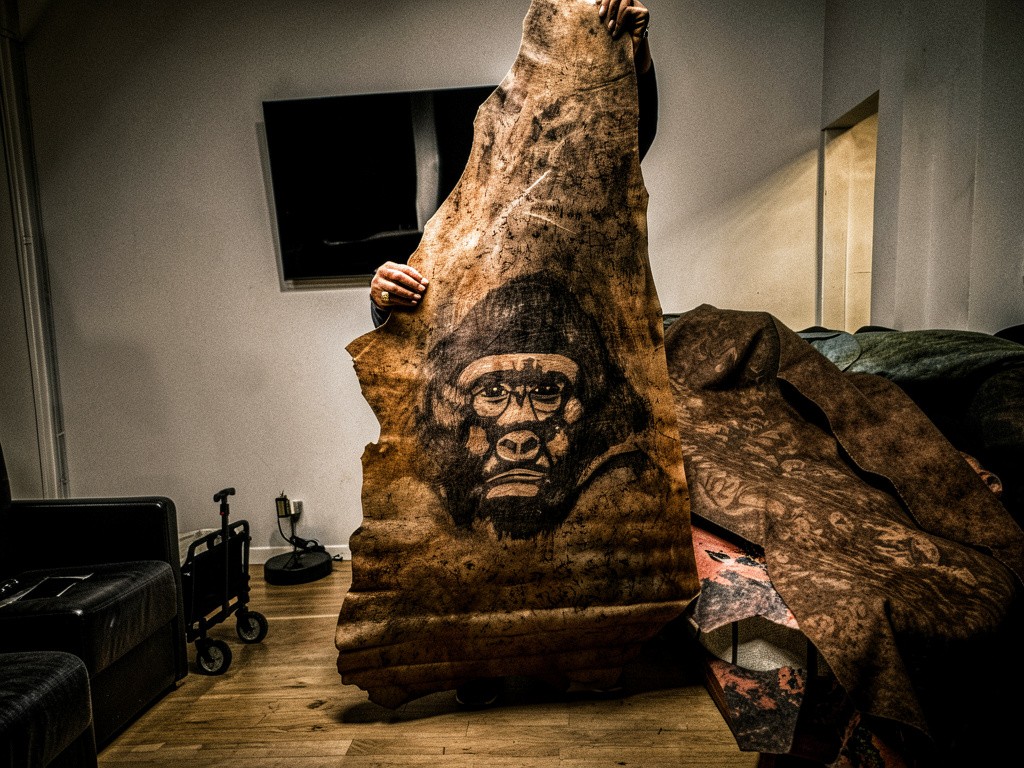 Young man in black leather double-breasted jacket jeans stand by white wall