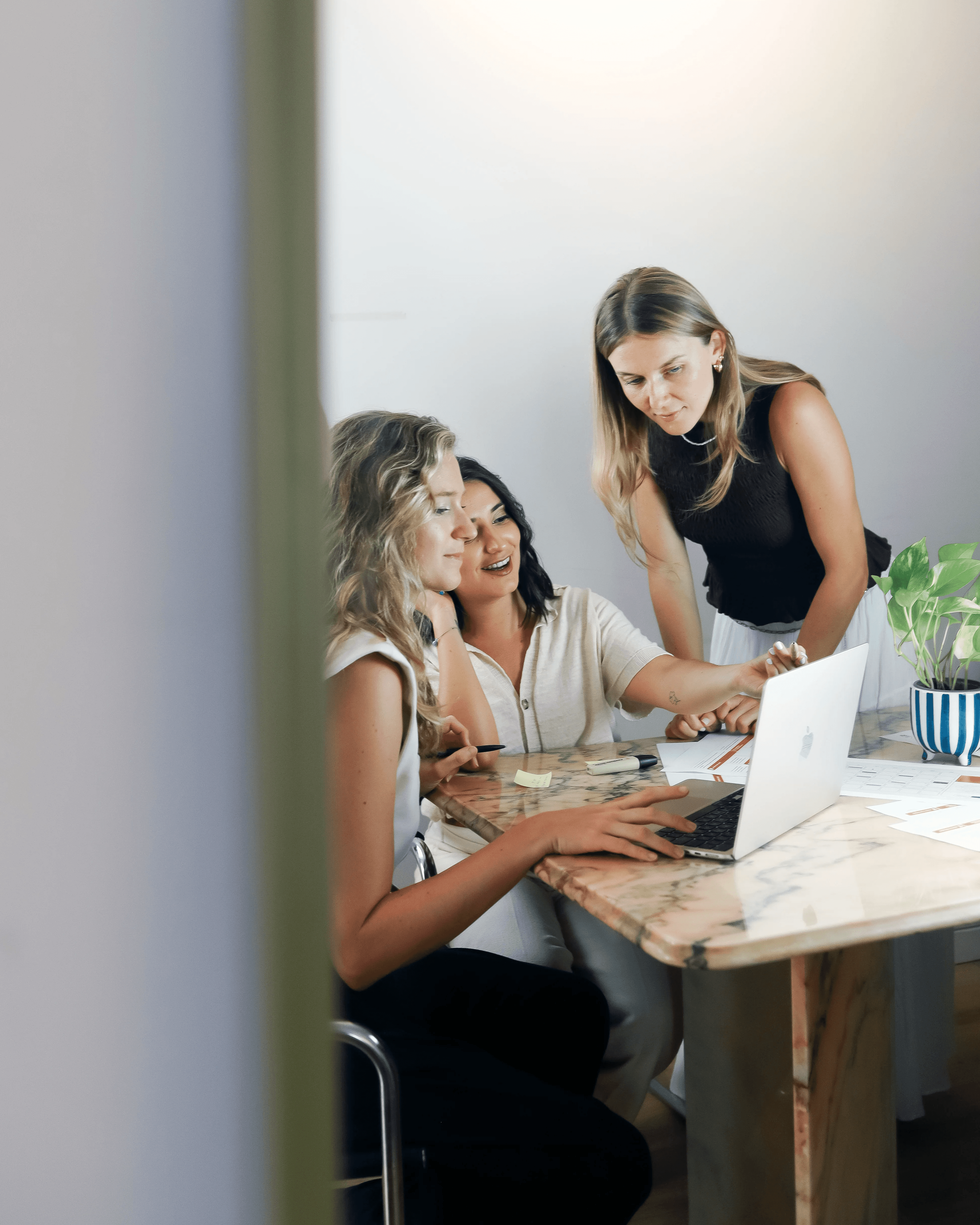 Team collaborating around a laptop during a strategic project meeting, reviewing documents and sharing ideas