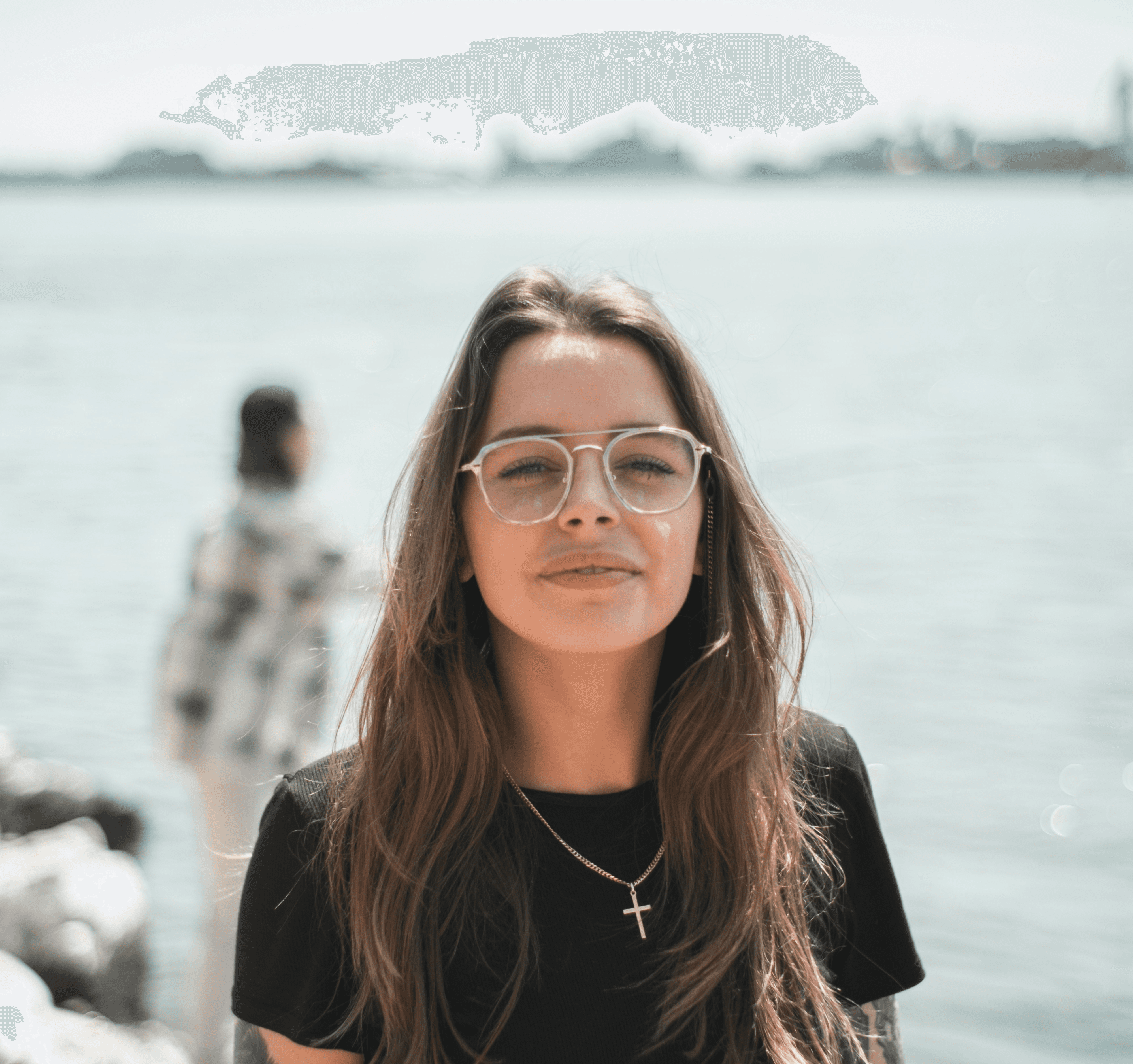 woman in black crew neck t-shirt wearing brown framed eyeglasses standing on rocky shore during
