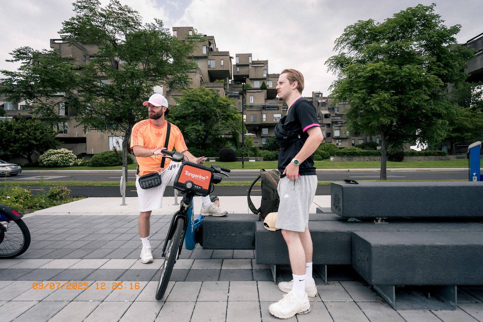 Deux hommes en tenue de sport discutent près de l’habitat 67 à Montréal.