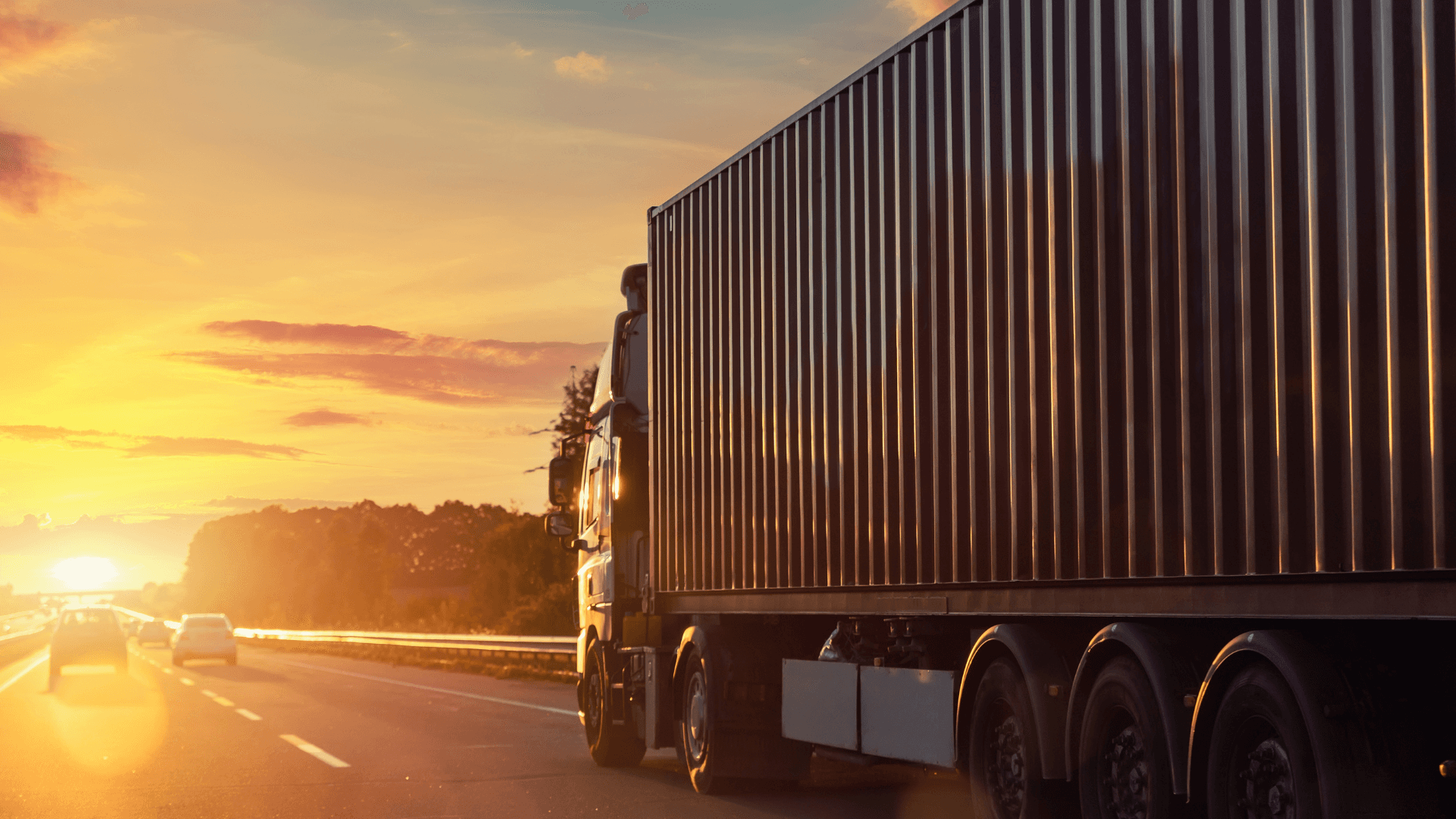 argo truck transporting a shipping container on a highway during sunset.