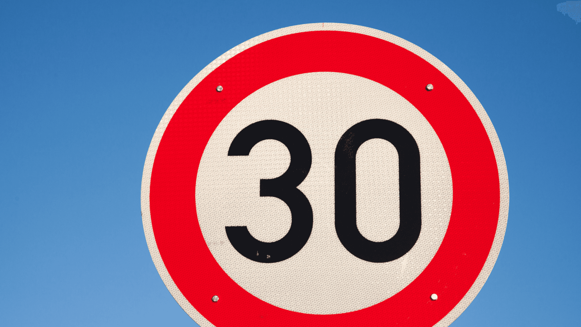 Eine Person in einem weißen Hemd hält ein Tablet, mit einem Stift in der Hand und einer roten Tasse in der Nähe auf einem Schreibtisch.