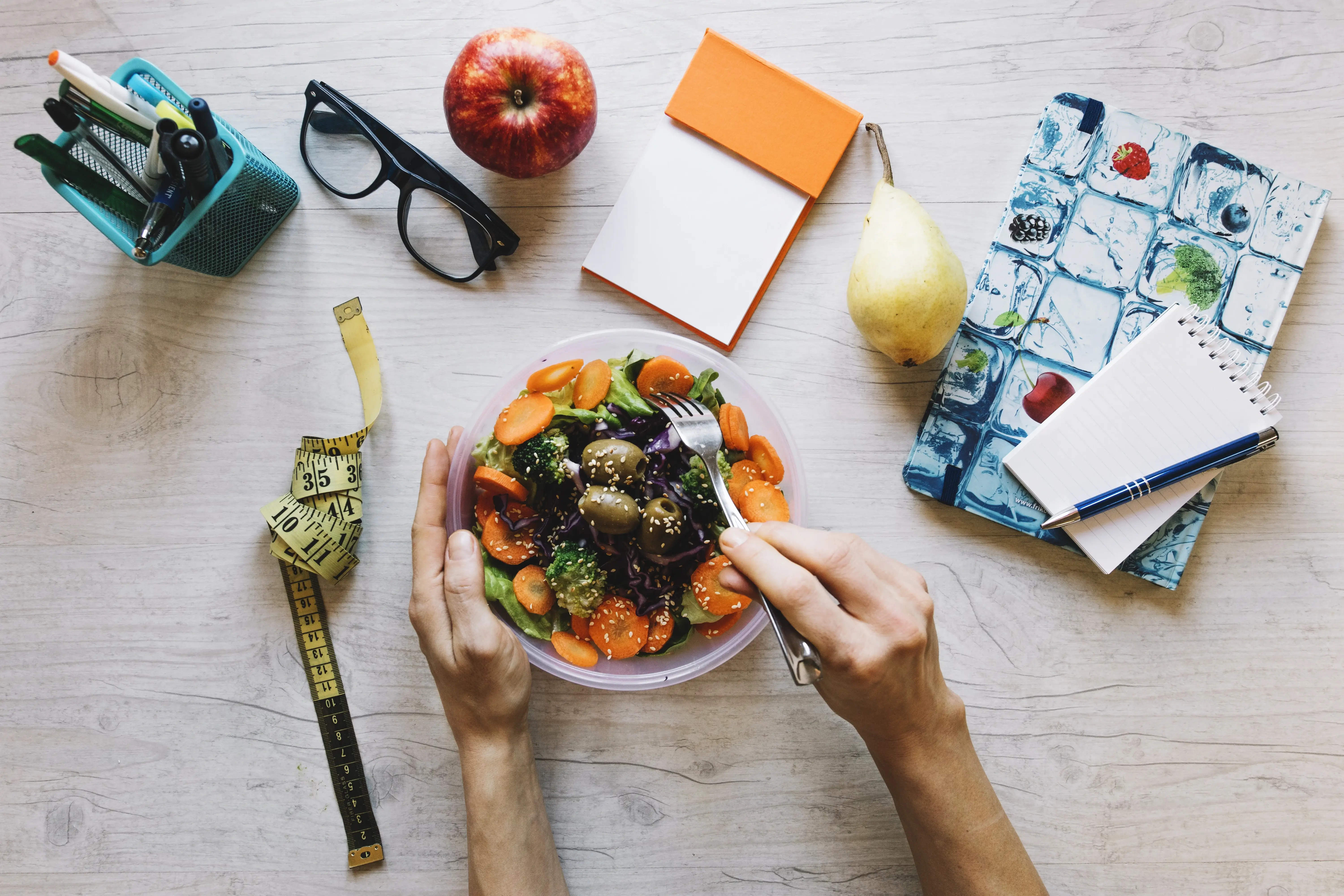 Manos sirviendo un bowl saludable con frutas y vegetales sobre una mesa de trabajo