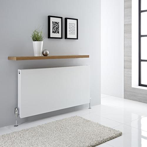 White panel radiator on a UK home wall connected to an air source heat pump system running at low flow temperature