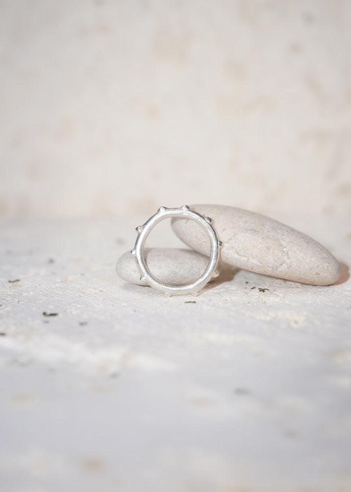 Silver ring on a white stone with a blurred natural background