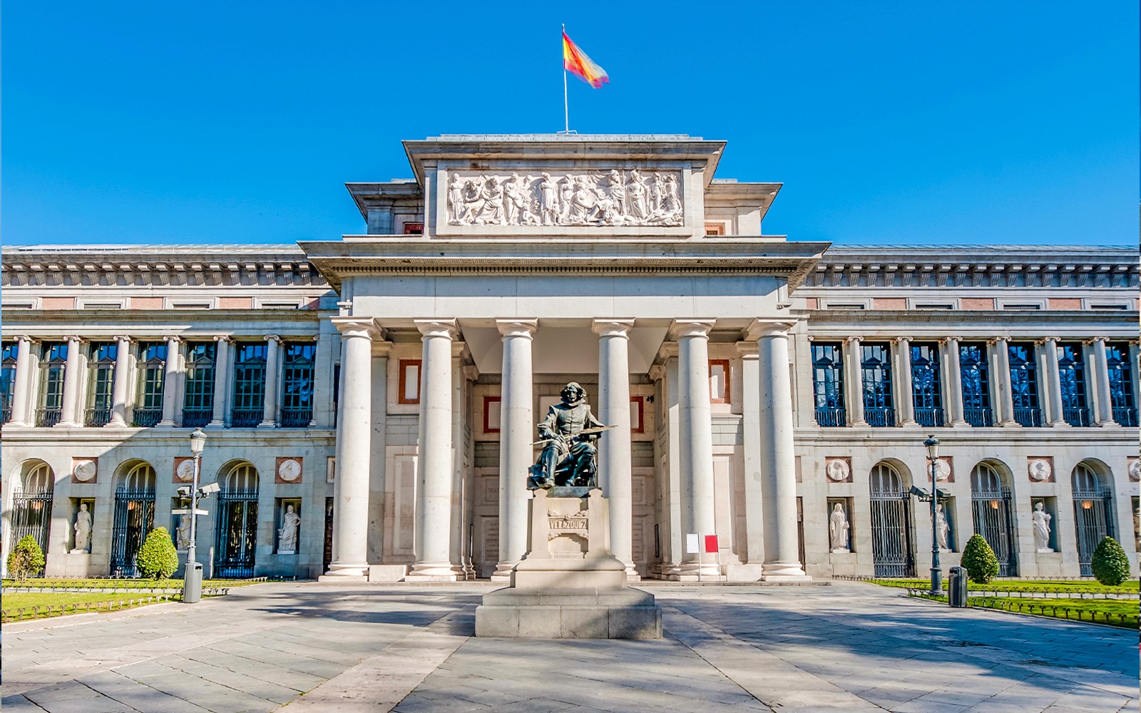 Ingresso al Museo del Prado a Madrid con statua e visitatori nelle vicinanze.