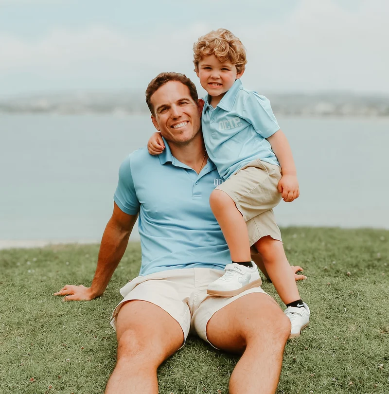 Tyler Watkins with his son, both wearing light blue OCIP shirts.