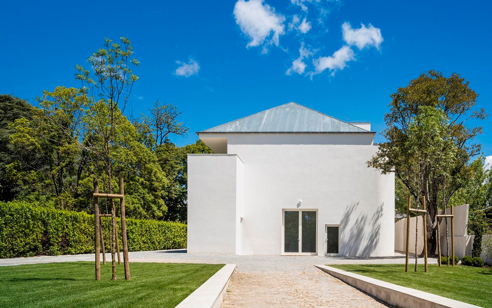 Modern fehér épület a portói Serralvesben, fákkal körülvéve, tiszta kék ég alatt.