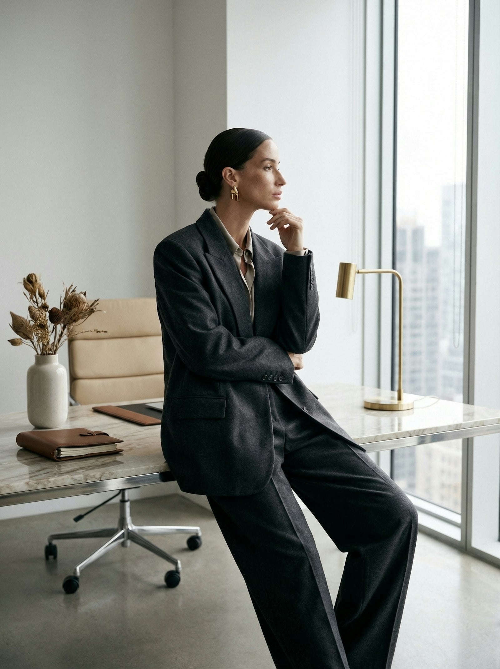 A member of the studio seated by the window, thinking, with a brass lamp on the desk.