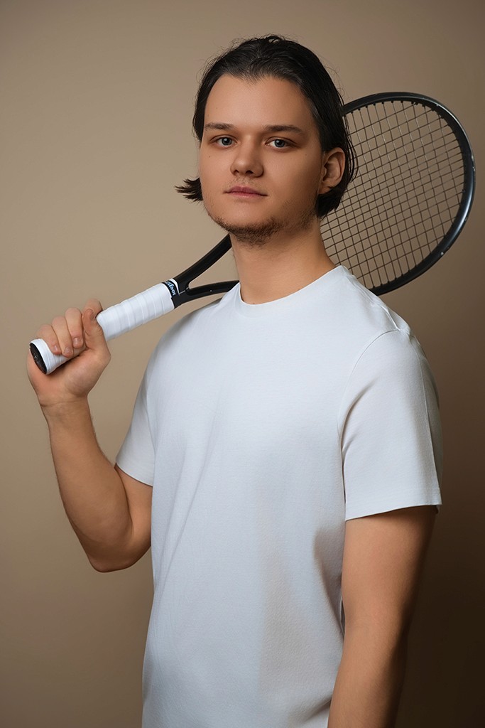 man in white crew neck t-shirt and black pants sitting on brown wooden fence during