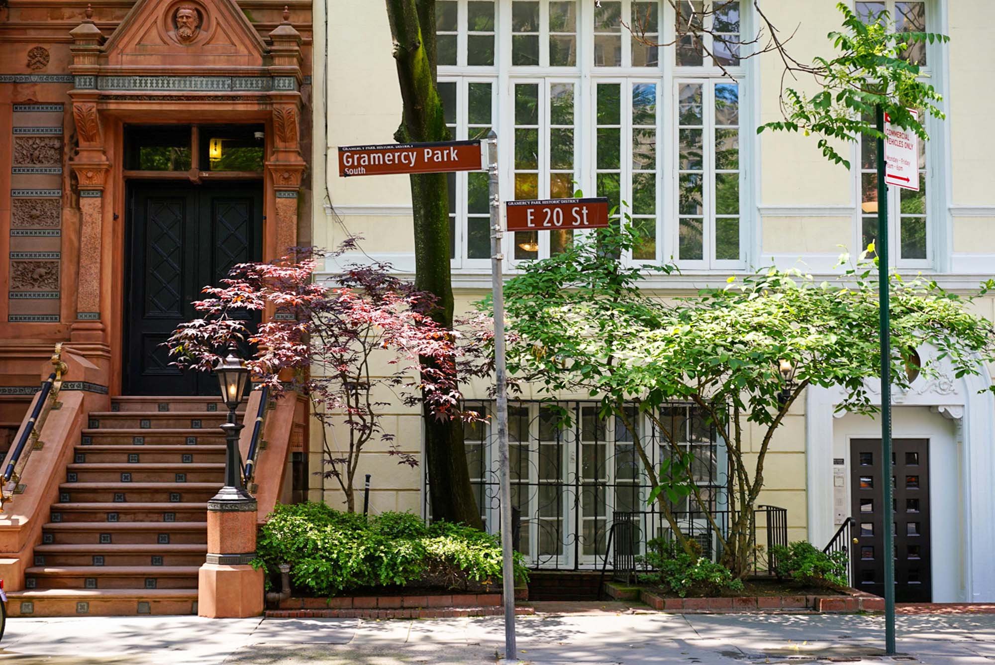 A red brick townhouse next to a yellow painted townhouse, the kind sold by BRN Partners, a Manhattan real estate brokerage