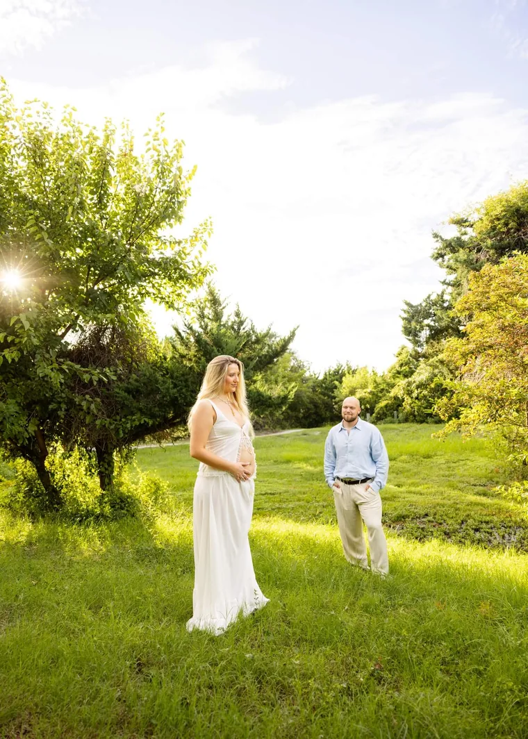 Couple standing in a sunlit green field surrounded by trees, by Sioux Falls, SD couples photographer Kelsey Lynn